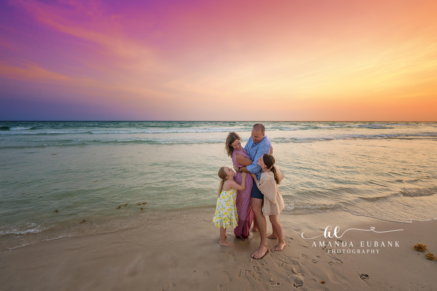 Family Embrace in Florals | Family Photographer in Tampa, Florida Family beach portraits in Tampa, FL showing a family of five embracing on the beach in floral dresses at pastel sunset.