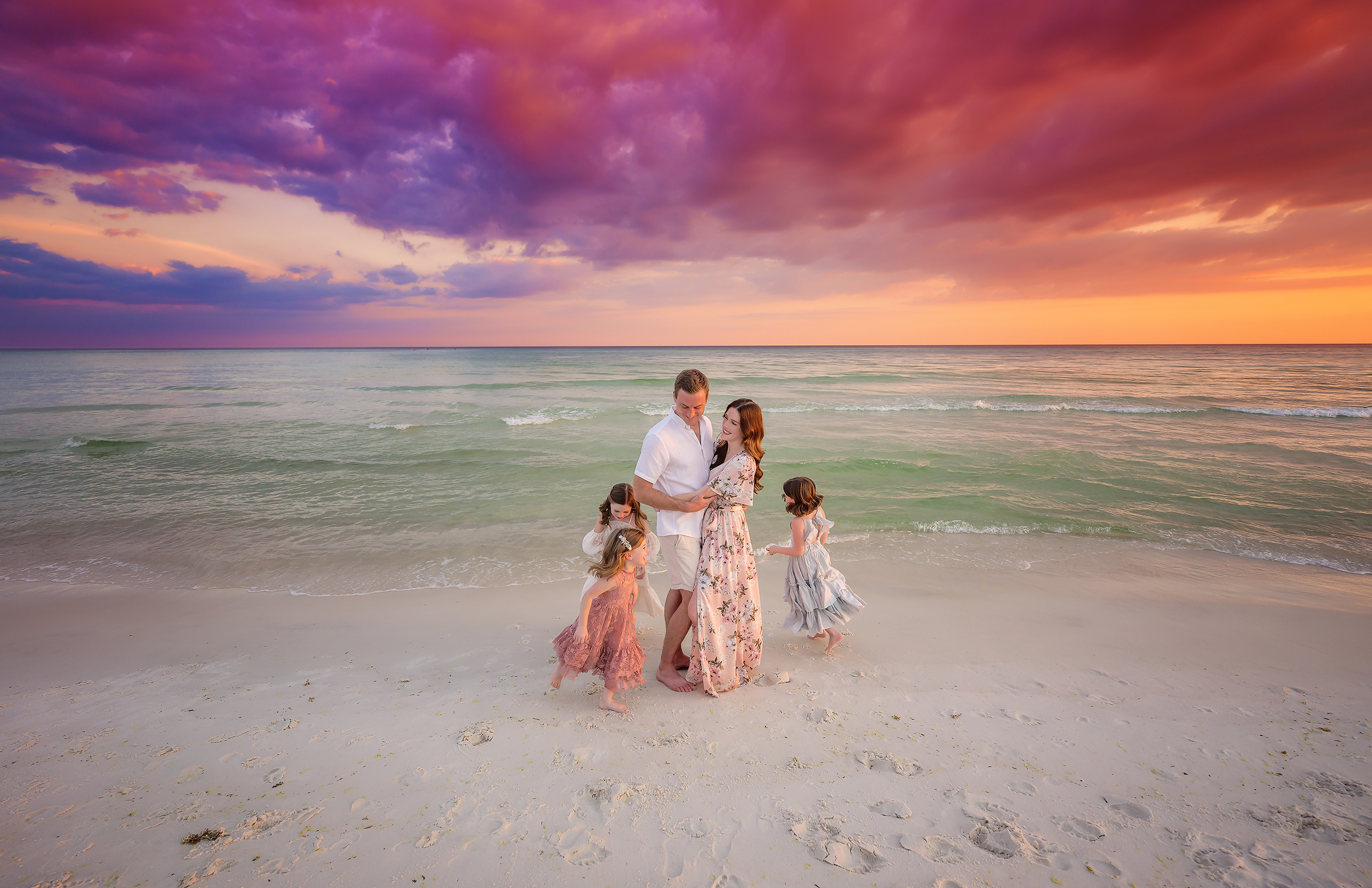 Blush Florals at Sunset — Tampa Bay Family Portraits A family of five standing on the sand in blush florals under purple clouds — beach family photography in Tampa Bay.