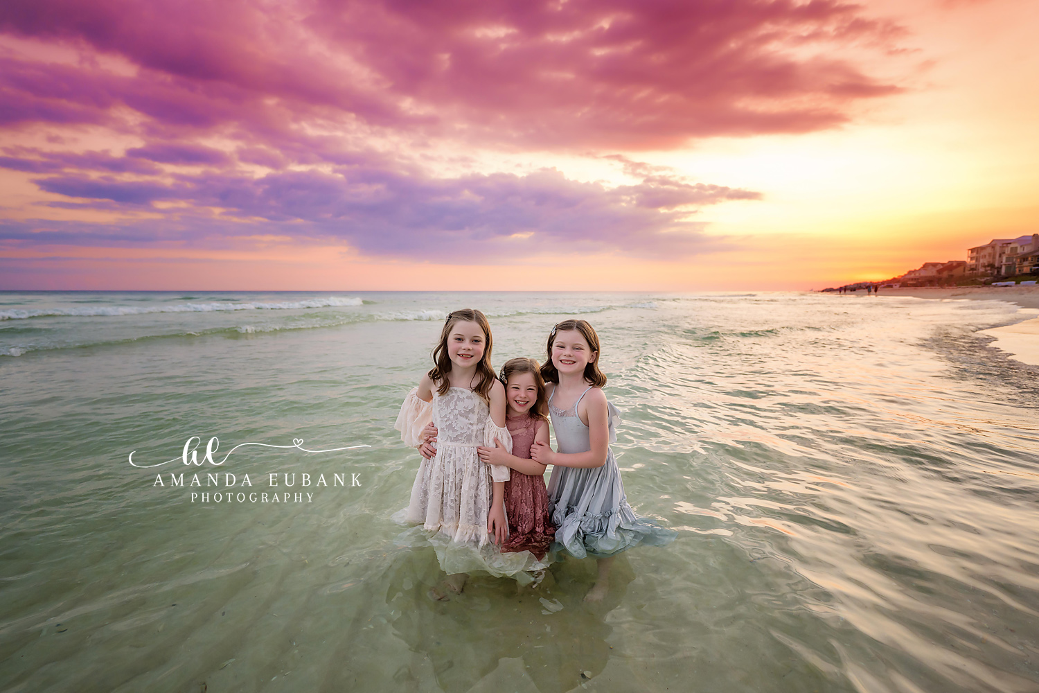Three Sisters in the Water — Tampa Bay Children’s Photography Three sisters standing together in the shallow water in white and blush at a beach kids session in Tampa, FL.