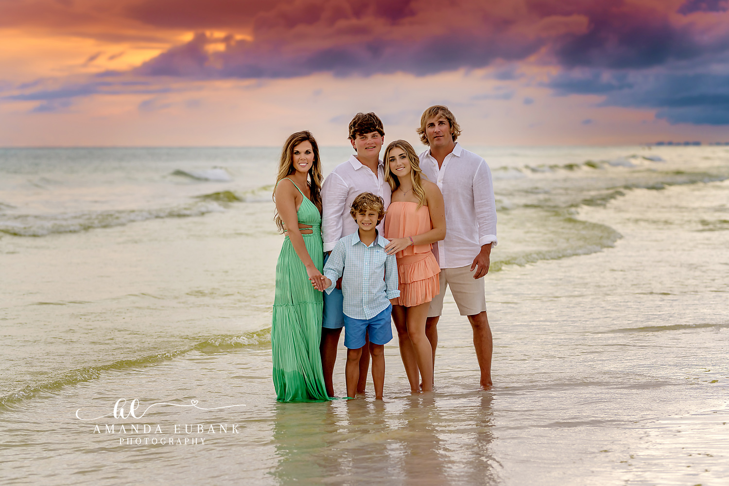 Family of Five in the Shallows | Family Photographer in Tampa, Florida Family beach portraits in Tampa, FL showing a family of five standing in the shallow surf in green, coral and white.