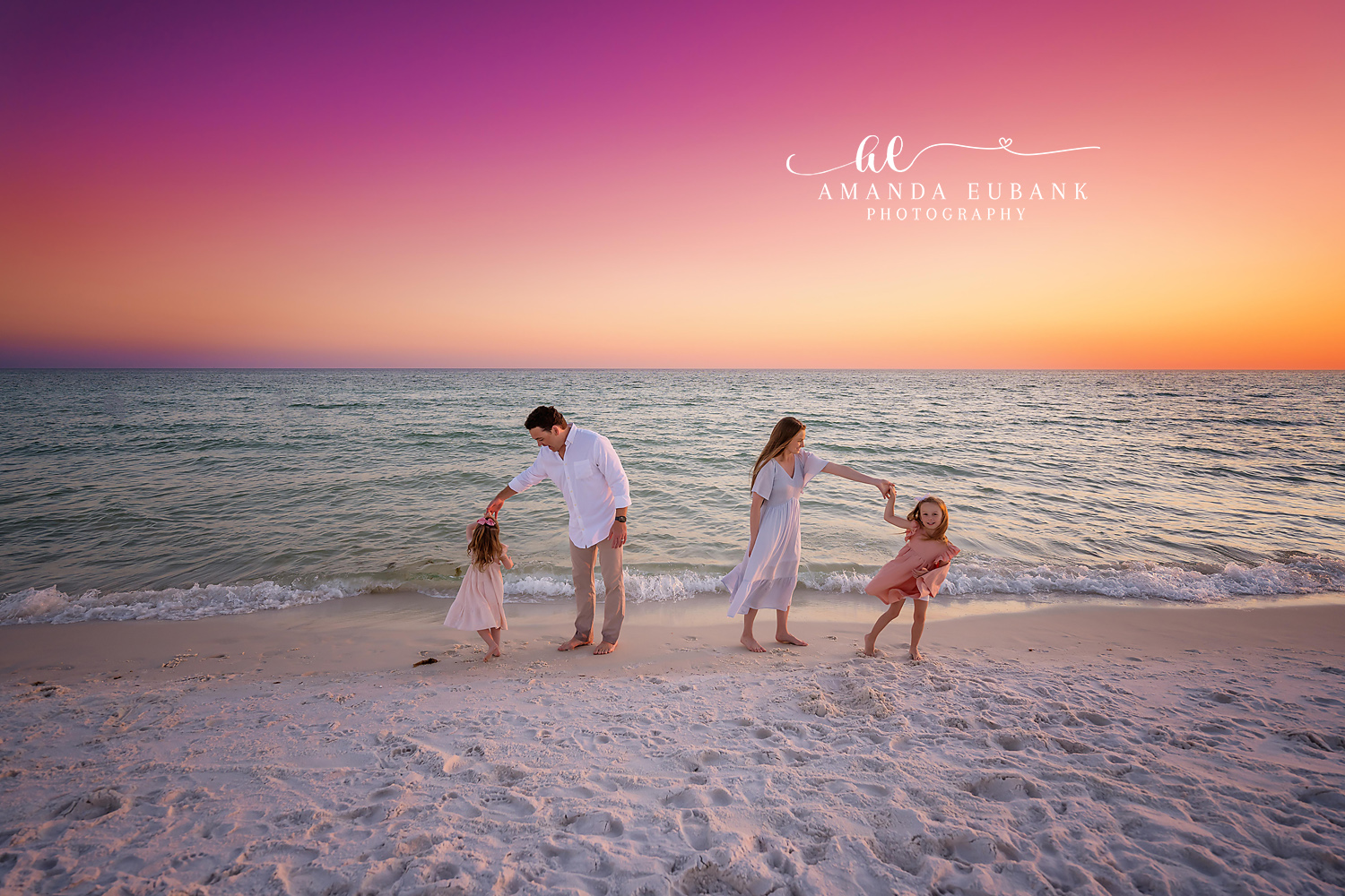 Circle of Hands on the Beach — Tampa, FL Family Session A family of five joining hands in a circle on the sand under a magenta sky at a beach family session near Tampa, Florida.