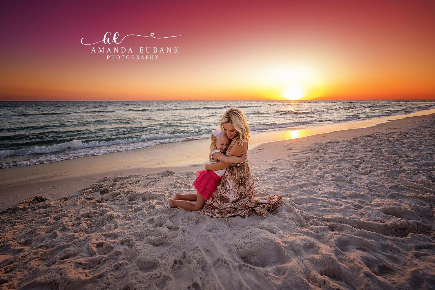 Mother and Daughter at Sunset | Tampa Family Photographer A mother and daughter sitting together on the sand as the sun meets the water during a Tampa family photography session.