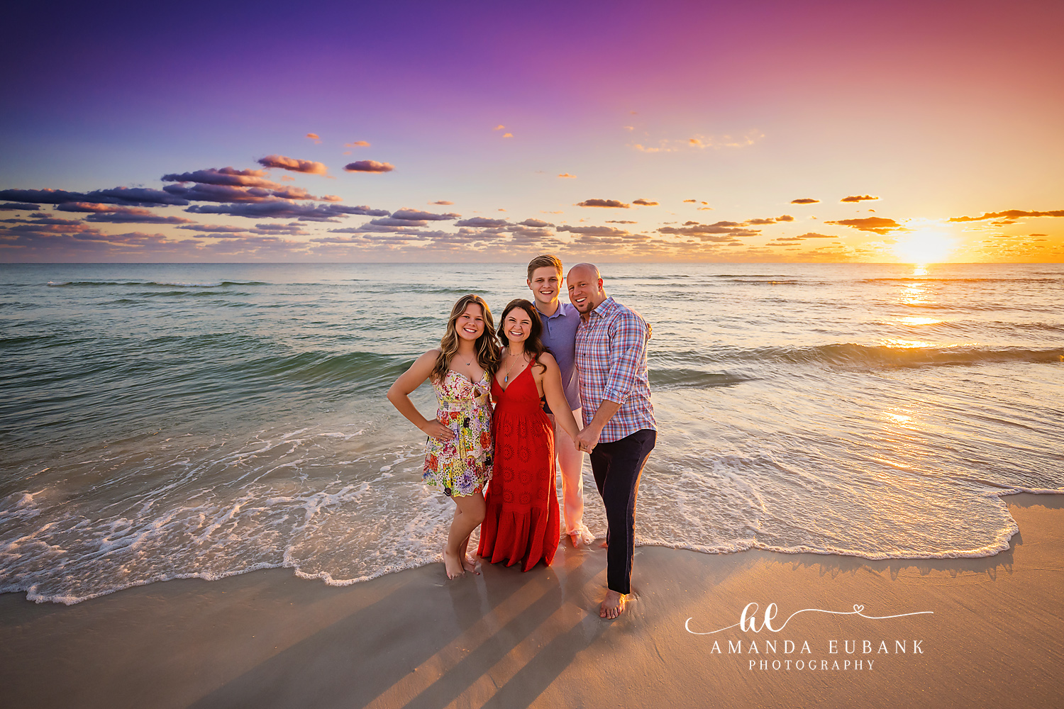 Family Portrait in Red and Floral | Tampa Family Photographer A family of four on the shoreline in red and floral beneath a pastel sky during a Tampa family photography session.