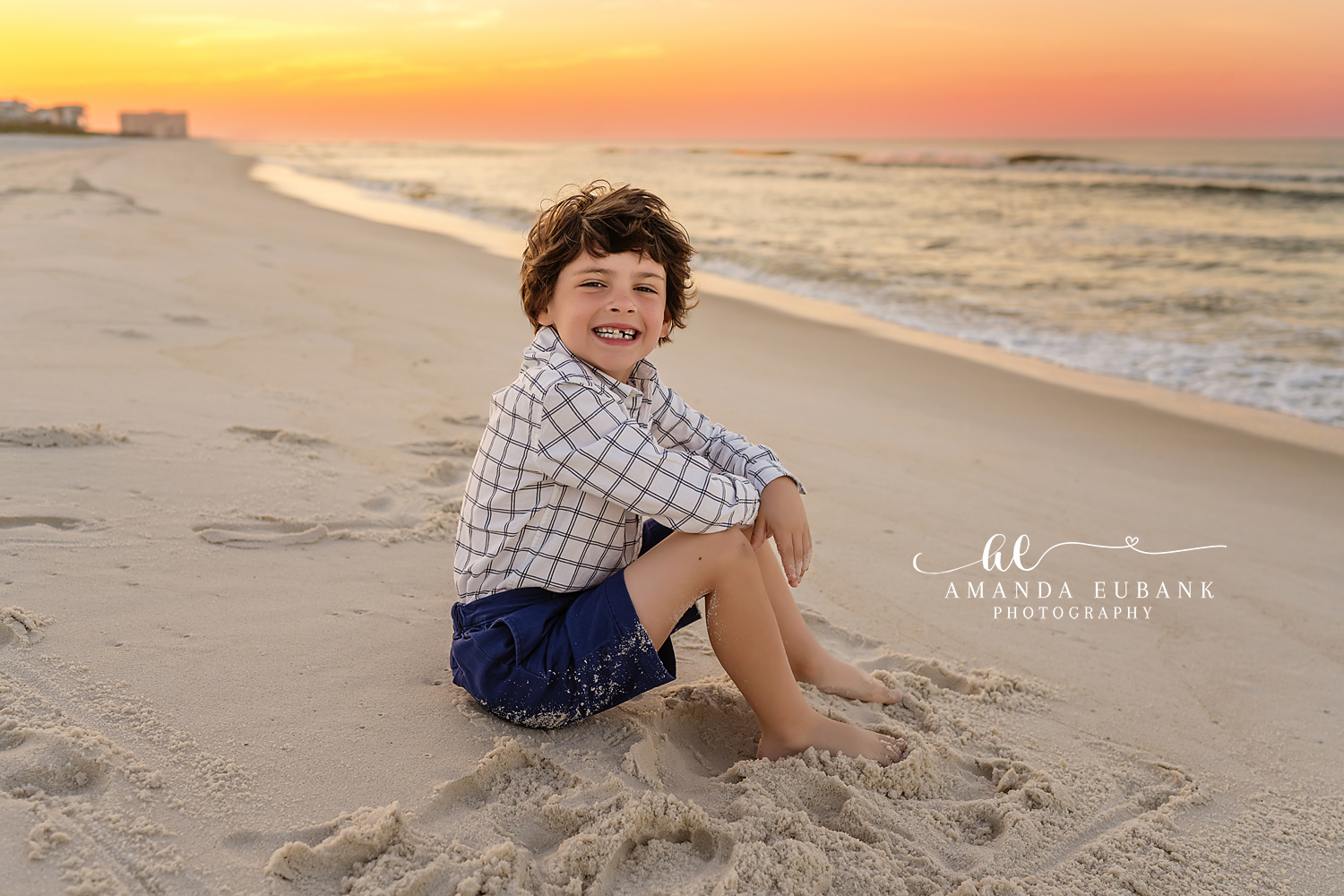 Boy Sitting on the Beach | Kids Beach Portraits in Tampa, FL Tampa children’s photographer captures a young boy in a plaid shirt sitting on the sand in soft evening light.