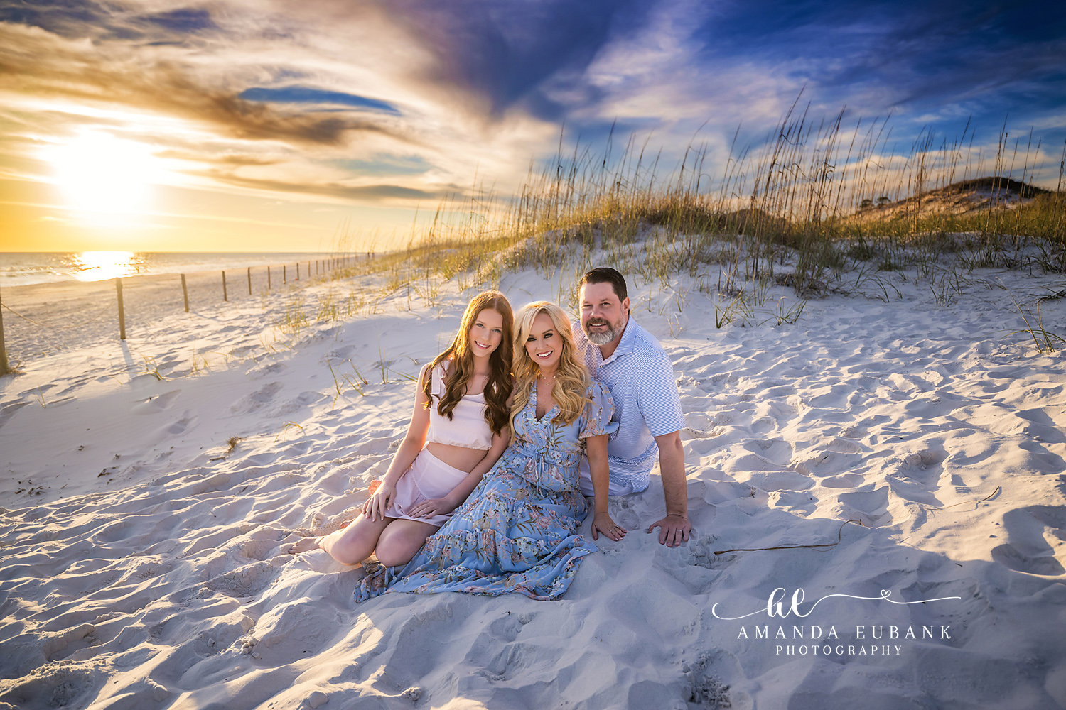 Family in the Dunes at Sunset | Tampa Beach Family Photography Tampa family photographer captures a family of four sitting in the dunes as the sun flares through the sea oats.