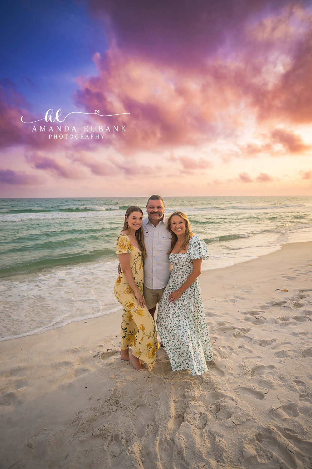 Mother and Daughter at Dusk — Tampa Bay Family Portraits A mother and daughter on the sand in yellow and floral beneath a purple sky — beach family photography in Tampa Bay.