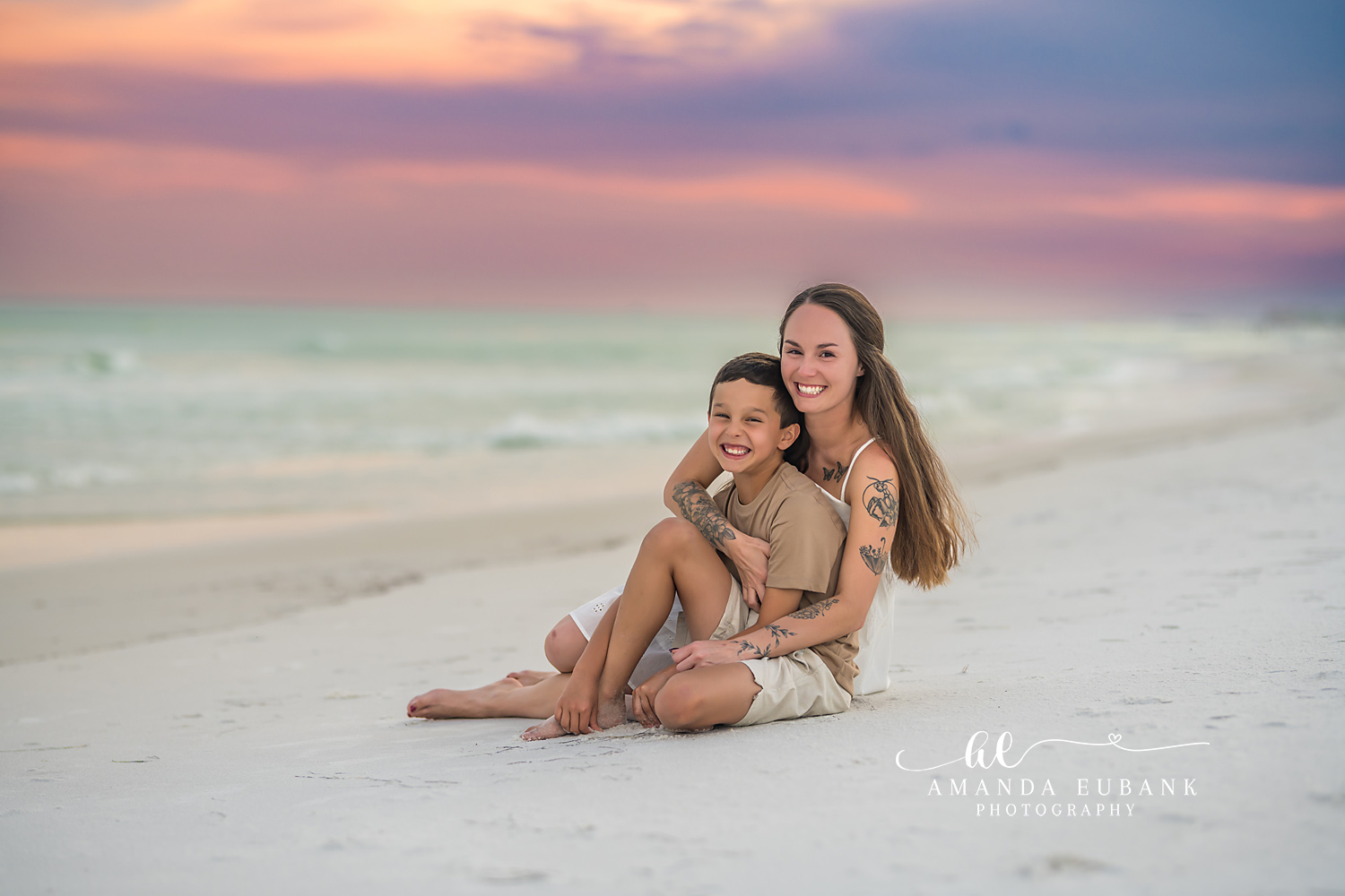 Mother and Son on the Beach | Tampa Family Photographer A mother and her son sitting together on the sand at pastel sunset during a Tampa family photography session.