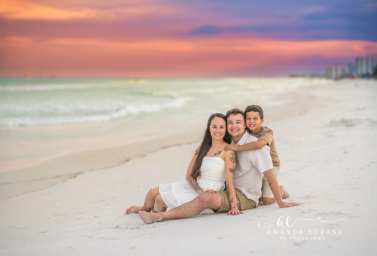 Couple in White on the Sand | Couples Photographer in Tampa, Florida Couples portraits in Tampa, FL showing a couple sitting on white sand in white and khaki beside the emerald Gulf.
