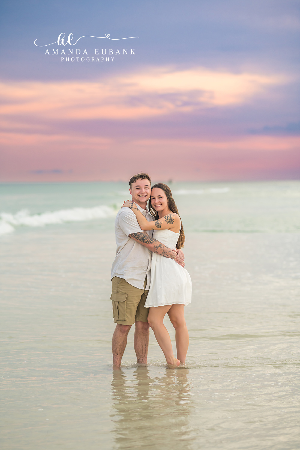 Couple Embracing at Dusk | Couples Photographer in Tampa, Florida Couples portraits in Tampa, FL showing a couple holding each other on the sand in white and khaki at dusk.