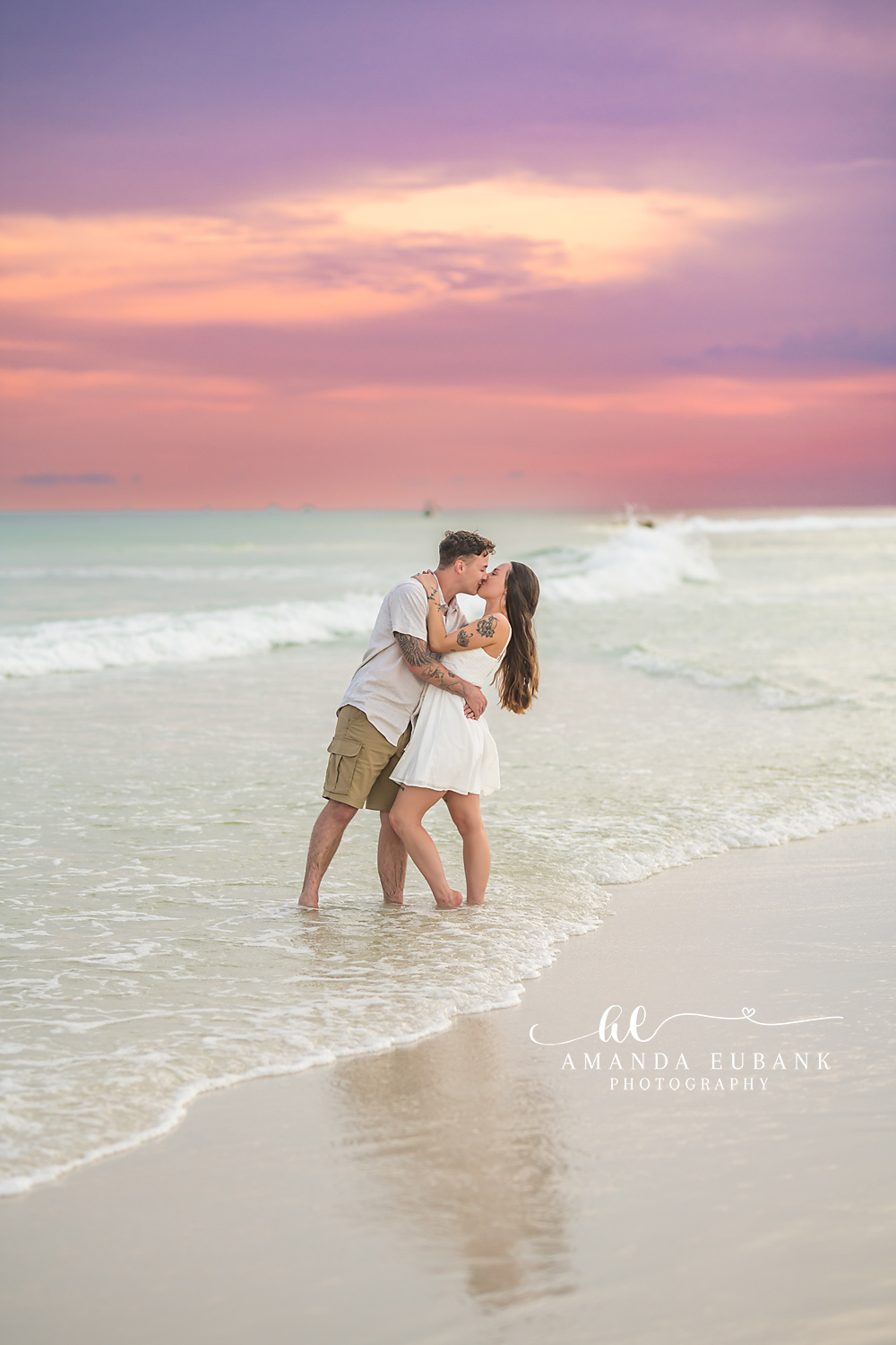 Kiss on the Wet Sand at Dusk | Tampa Couples Photographer A couple kissing on the wet sand under a pink and purple evening sky during a Tampa couples photography session.