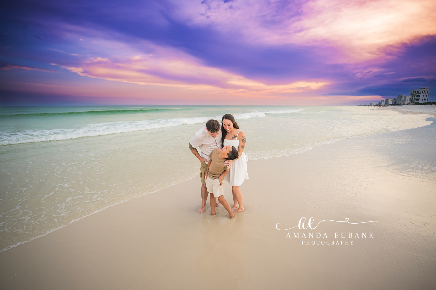 Couple in the Shallows at Sunset | Tampa Beach Couples Photography Tampa couples photographer captures a couple embracing in the shallow water beneath a violet and gold sky.