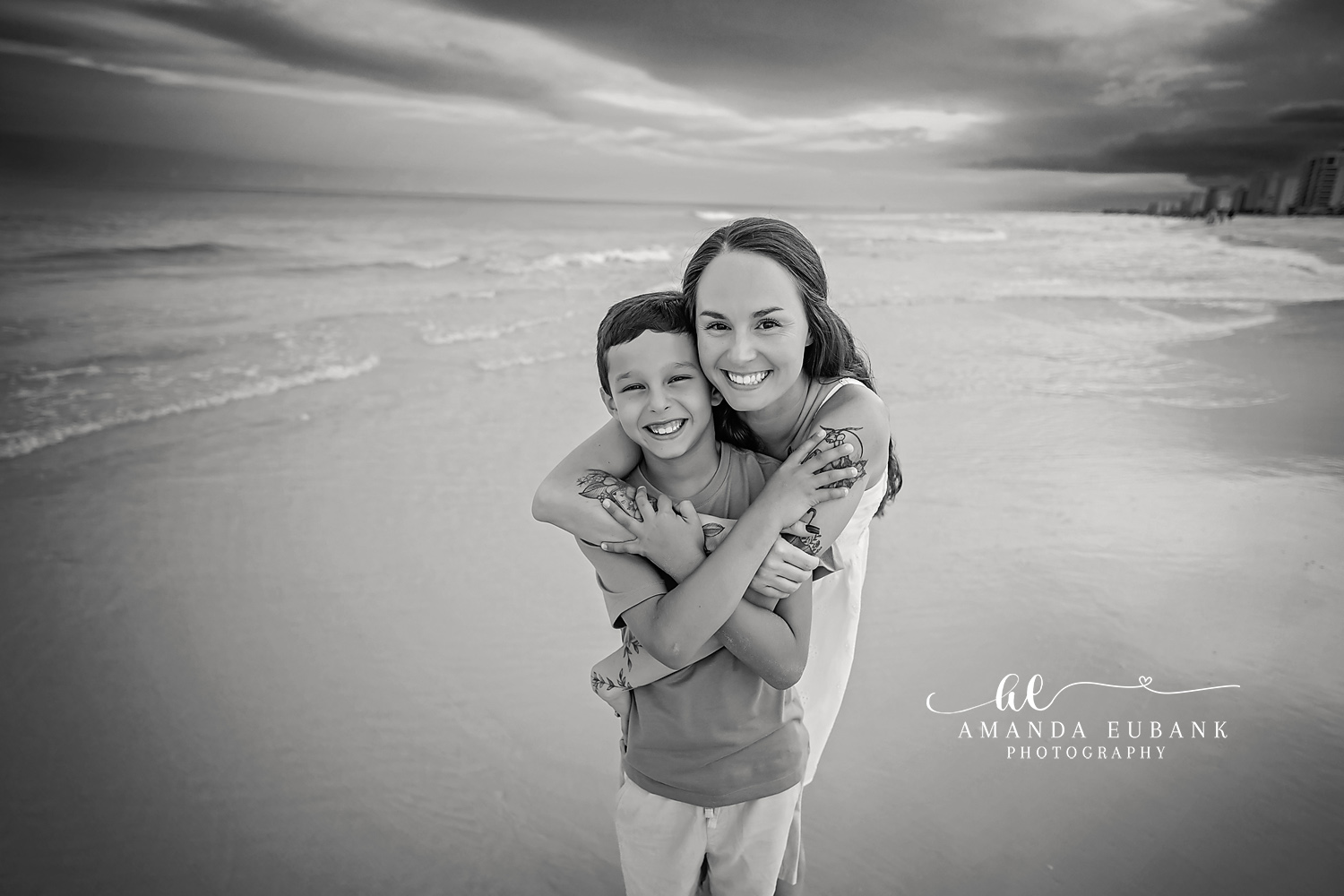 Mother and Son in Black and White | Family Photographer in Tampa, Florida Family beach portraits in Tampa, FL showing a black and white portrait of a mother holding her son on the shoreline.