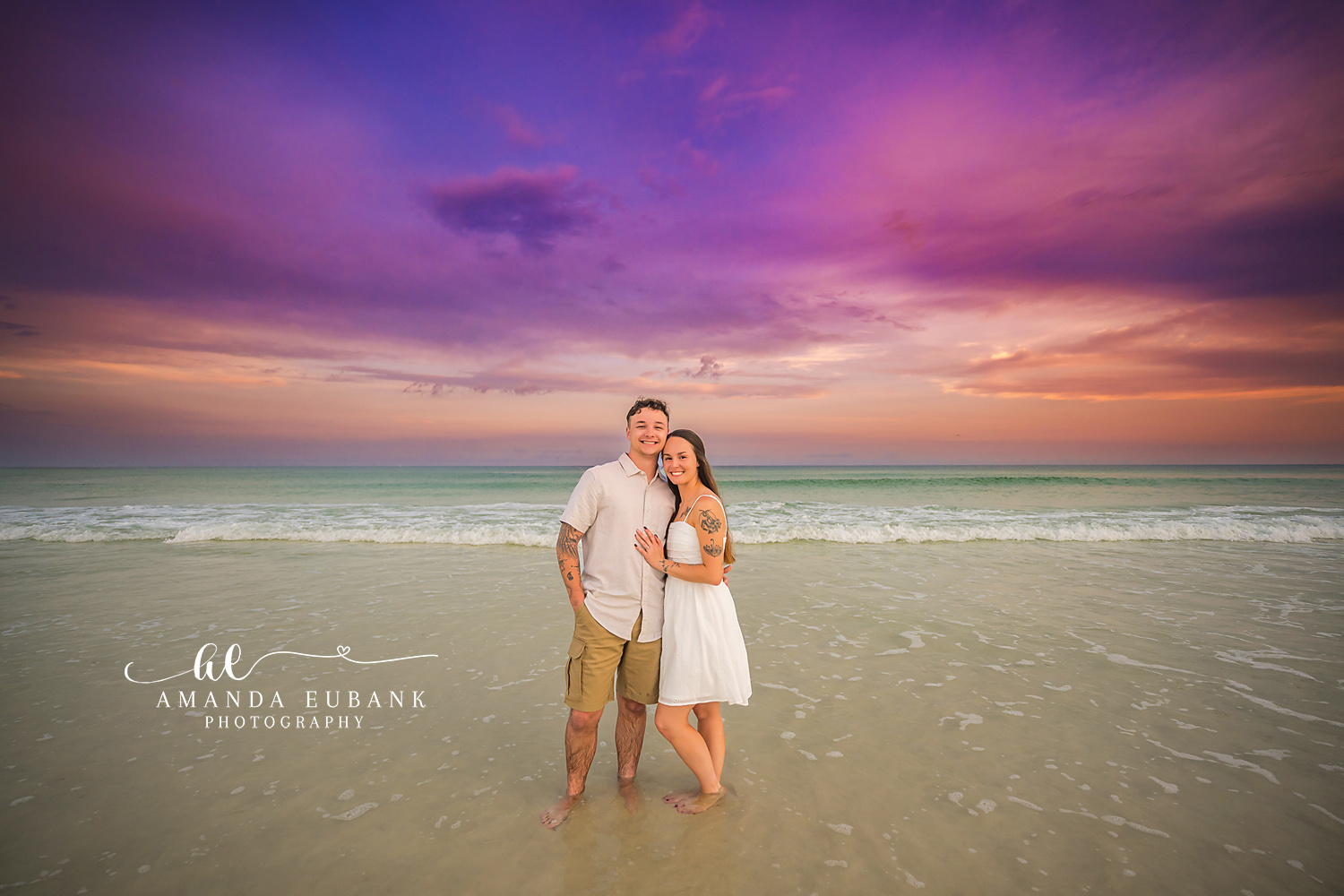 Family of Three in the Shallows | Tampa Beach Family Photography Tampa family photographer captures a family of three standing in the shallow water in white and khaki at dusk.