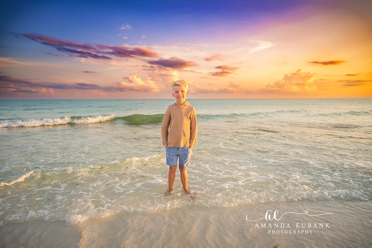 Boy in the Shallow Water — Tampa Bay Children’s Photography A young boy standing in the shallow water as the sky glows gold behind him at a beach kids session in Tampa, FL.