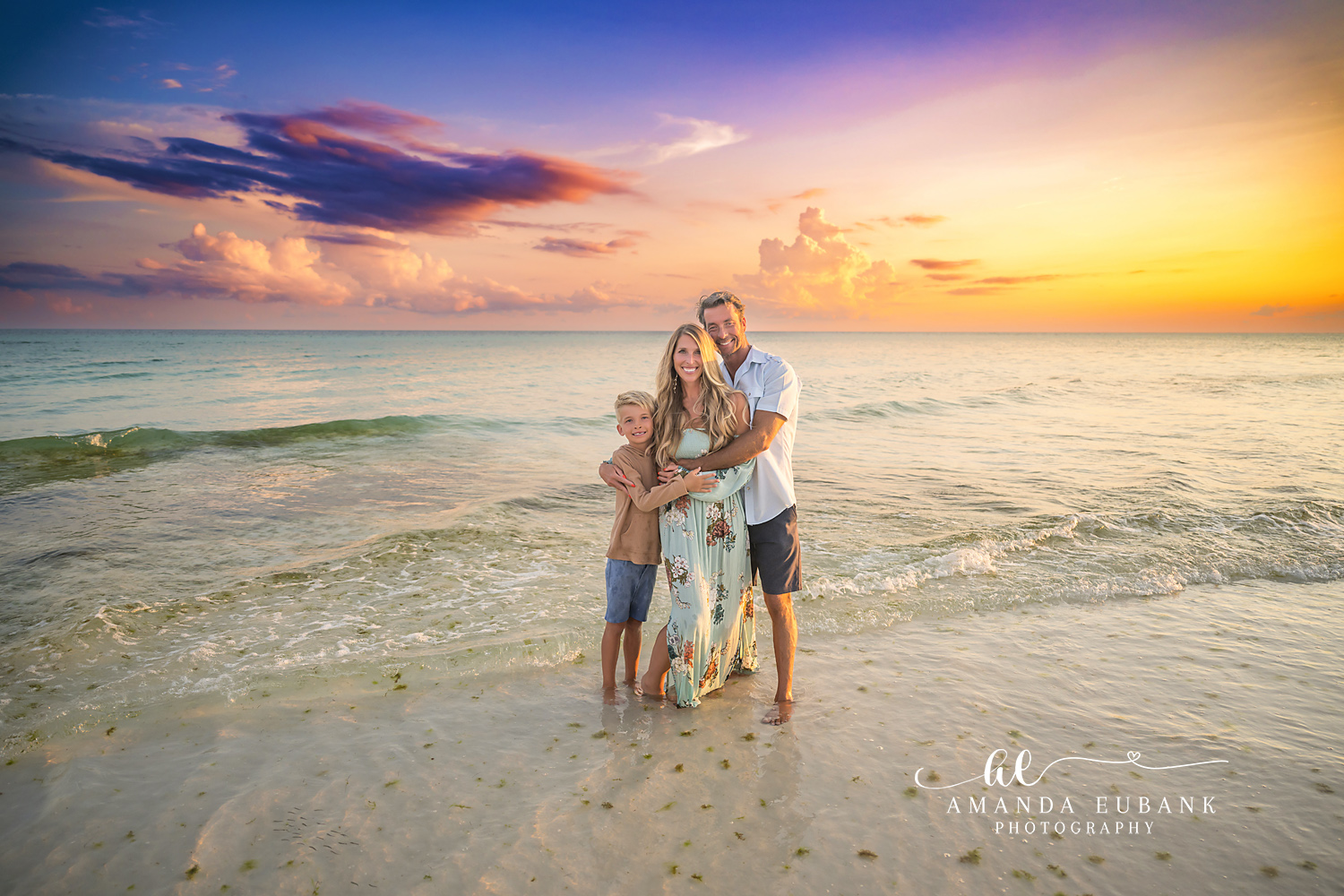 Family of Three at Golden Hour — Tampa Bay Family Portraits A family of three holding each other in the shallows as the sun sets — beach family photography in Tampa Bay.