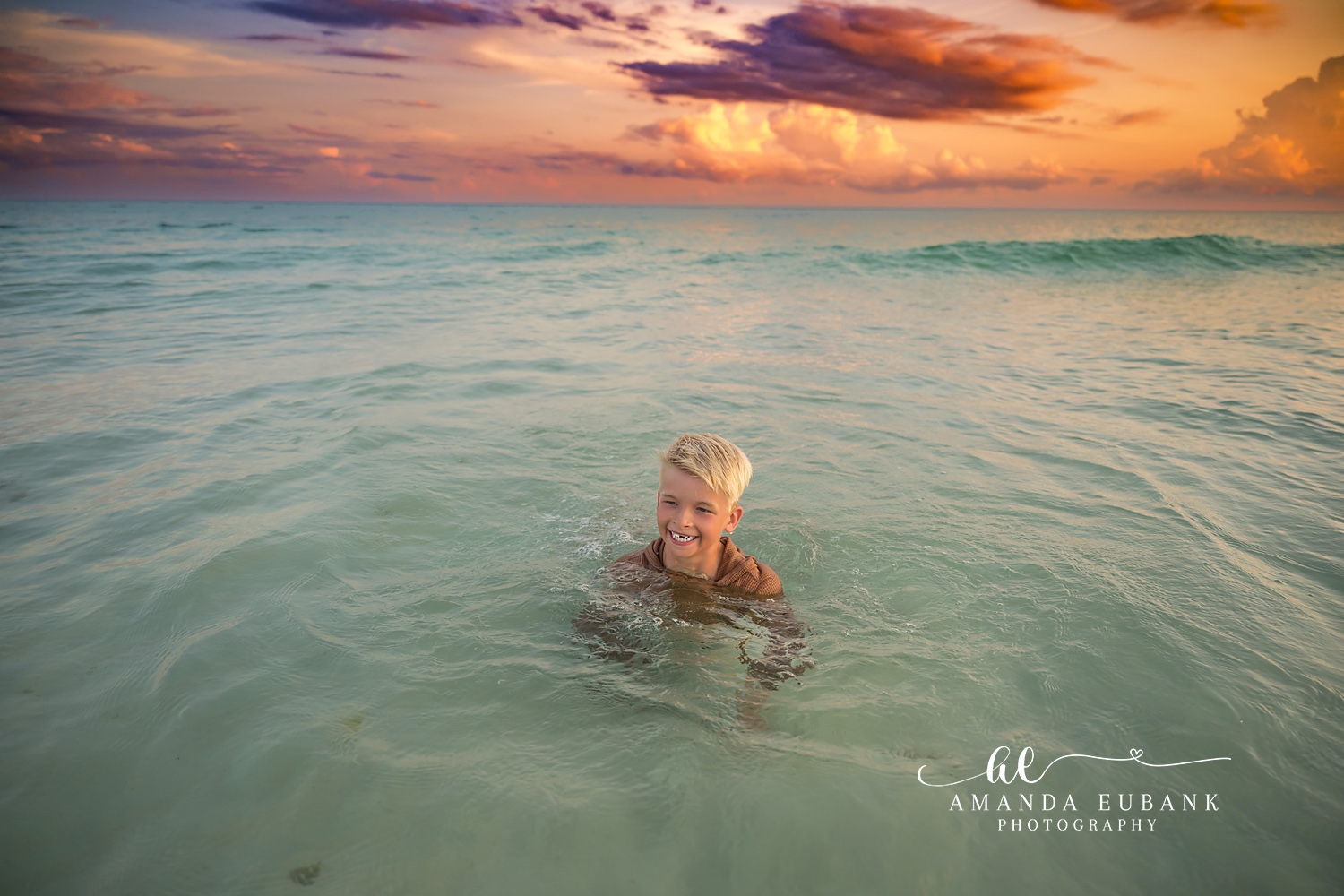 Boy Swimming in the Gulf — Tampa Bay Children’s Photography A boy swimming in the clear green Gulf water beneath a glowing sunset sky at a beach kids session in Tampa, FL.