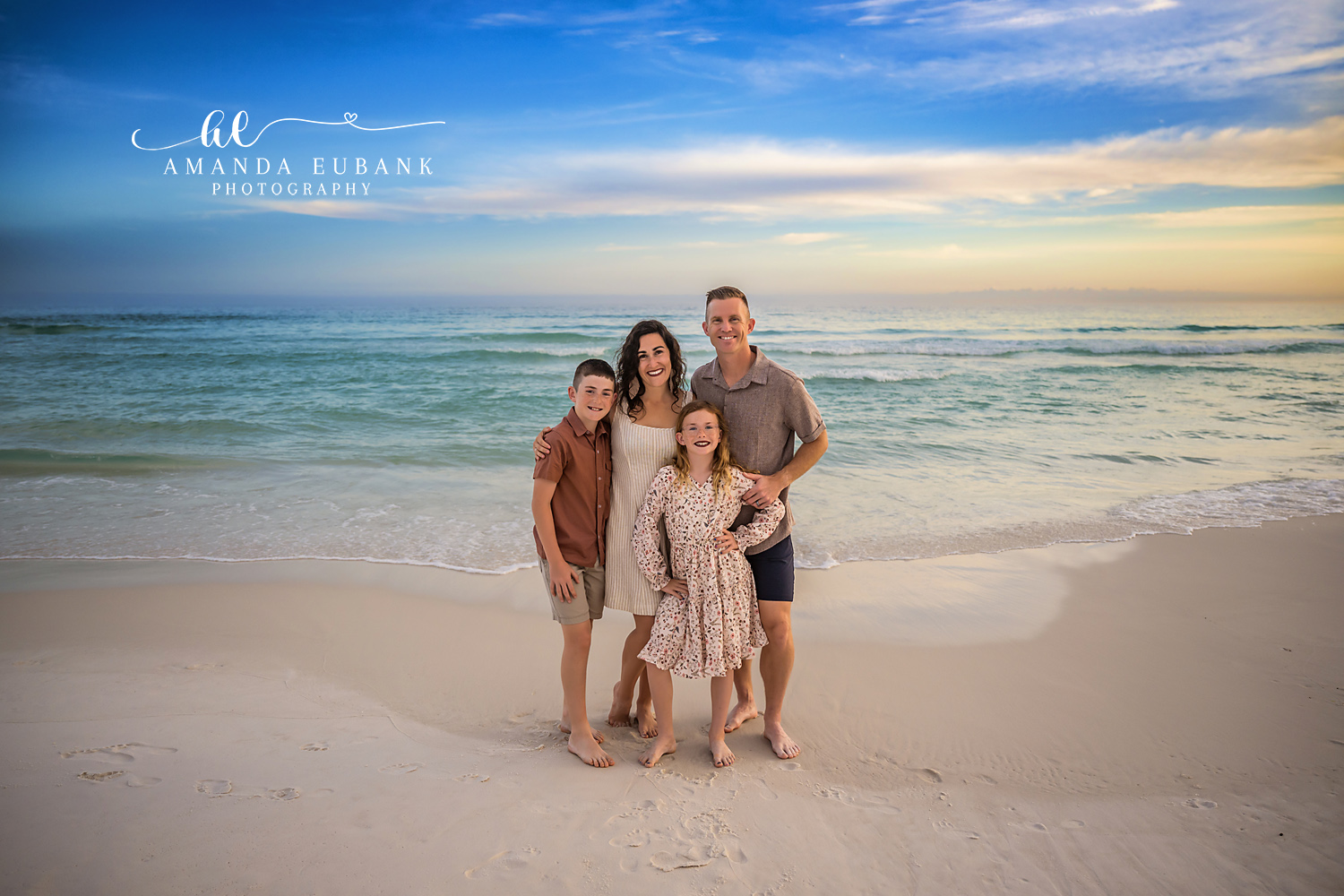 Family of Five in Rust and Cream — Tampa, FL Family Session A family of five standing on the sand in rust and cream beneath a blue and gold sky at a beach family session near Tampa, Florida.