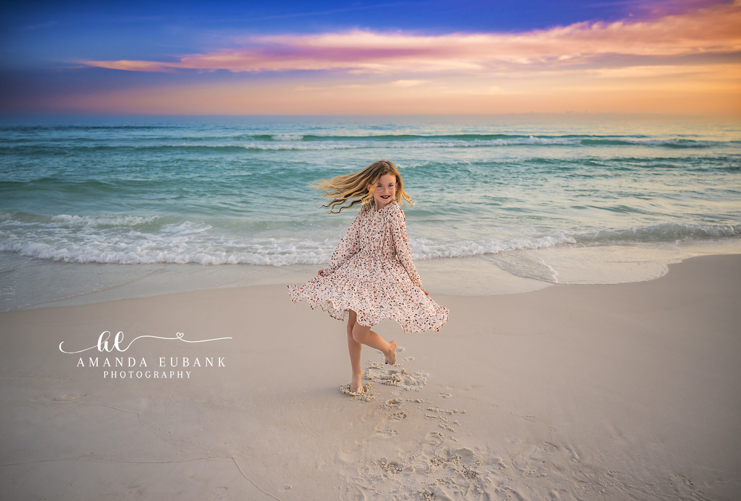 Girl Twirling on the Shoreline — Tampa Bay Children’s Photography A girl in a floral dress twirling on the shoreline as the sky glows pastel at a beach kids session in Tampa, FL.