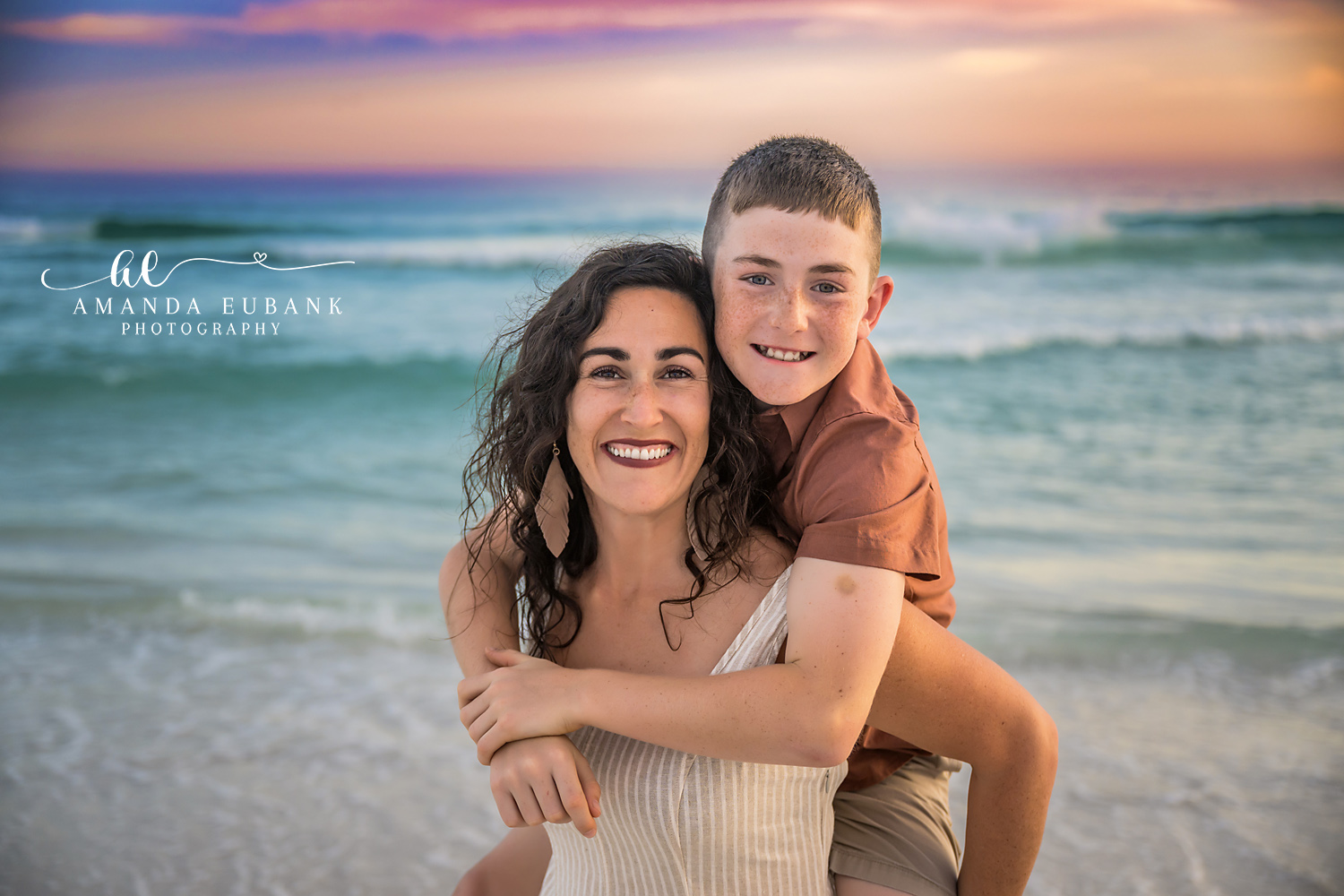 Mom and Son Piggyback | Tampa Family Photographer A laughing mother giving her son a piggyback ride with the Gulf behind them during a Tampa family photography session.