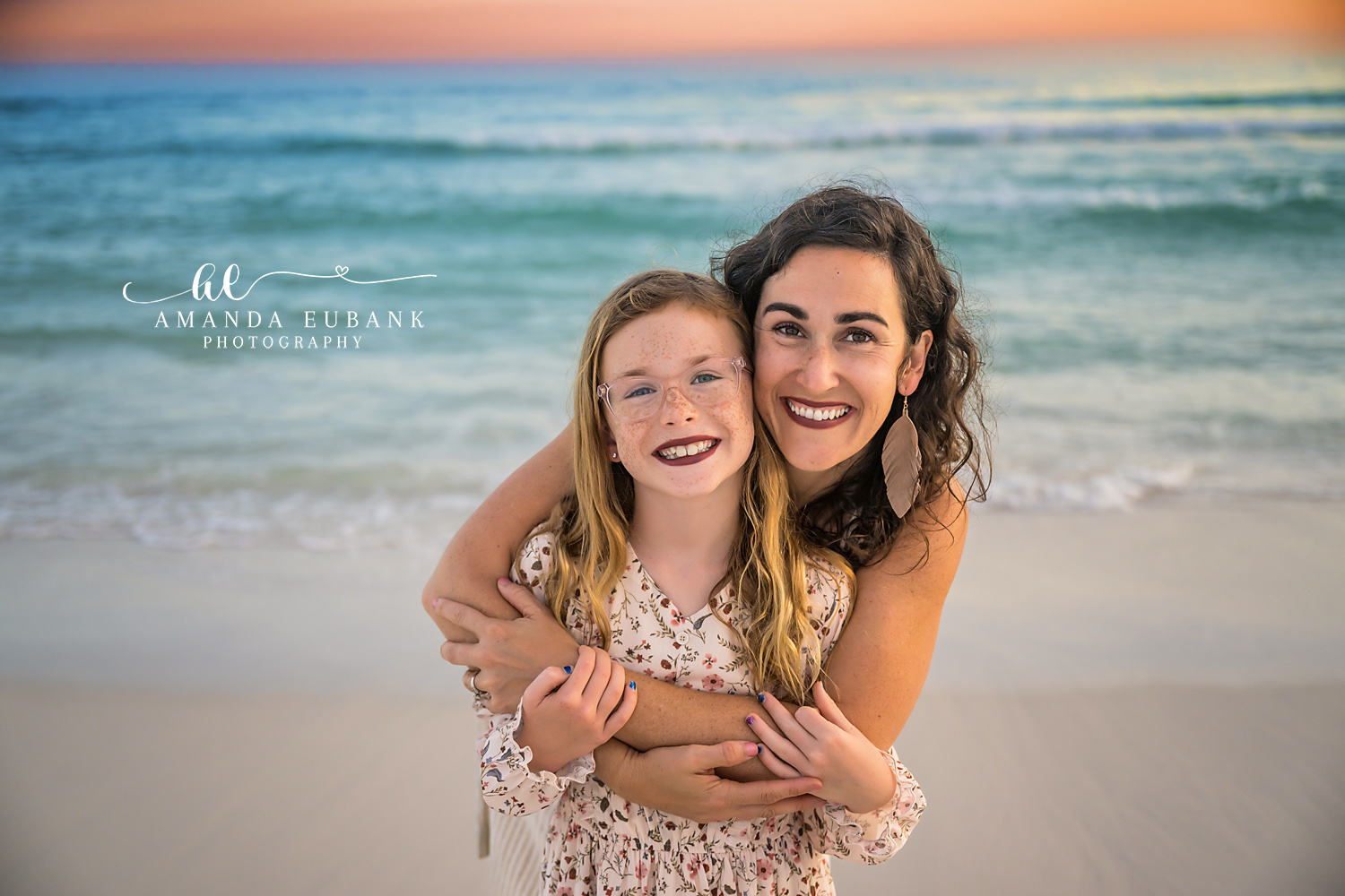 Mother and Daughter in the Surf — Tampa Bay Family Portraits A mother hugging her daughter from behind at the water's edge, both laughing — beach family photography in Tampa Bay.