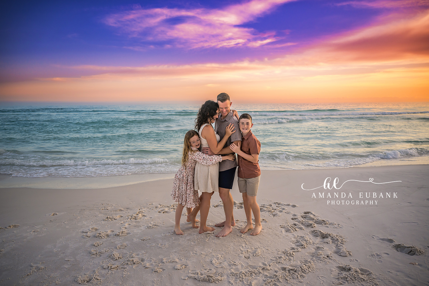 Family in Rust and Floral | Family Photographer in Tampa, Florida Family beach portraits in Tampa, FL showing a family of five standing together on the sand in rust and floral at dusk.