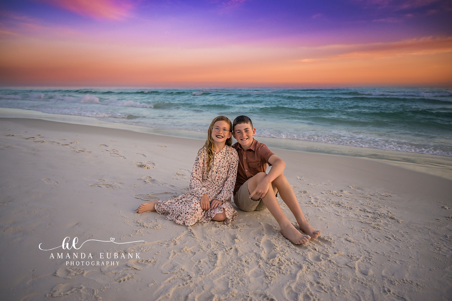 Couple Sitting Close on the Sand — Tampa Bay Couples Portraits A couple sitting close together on the sand under a violet and orange sky — beach couples photography in Tampa Bay.