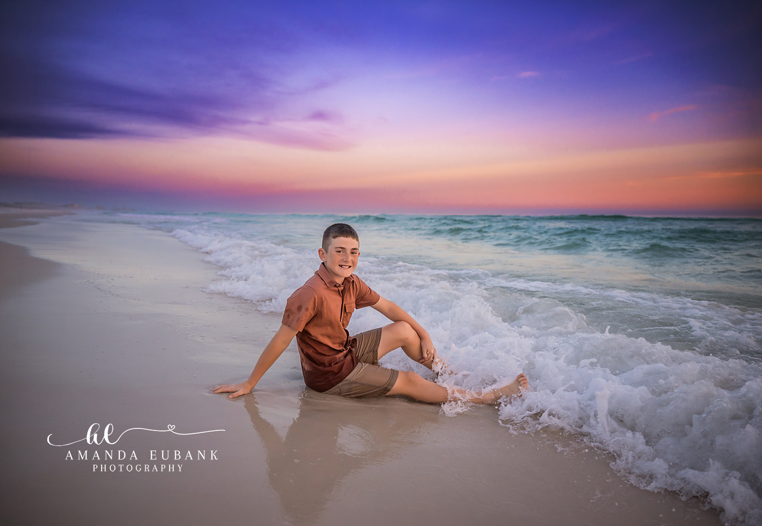 Boy Sitting on the Wet Sand | Tampa Children’s Photographer A boy sitting on the wet sand as a wave slides in beneath a violet sky during a children’s portrait session in Tampa, Florida.