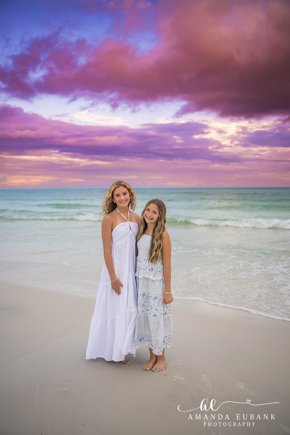 Mother and Daughter in White | Tampa Beach Family Photography Tampa family photographer captures a mother and daughter standing together in white dresses under a purple sky.