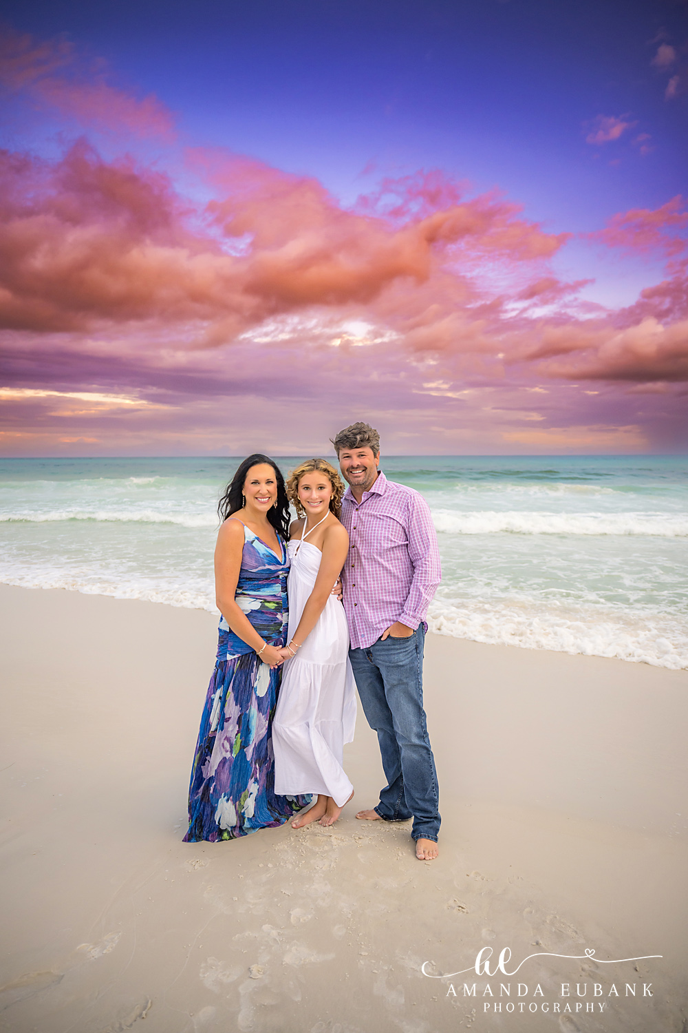Family of Three in Pink and Navy | Tampa Family Photographer A family of three standing close on the sand in pink and navy at pastel dusk during a Tampa family photography session.