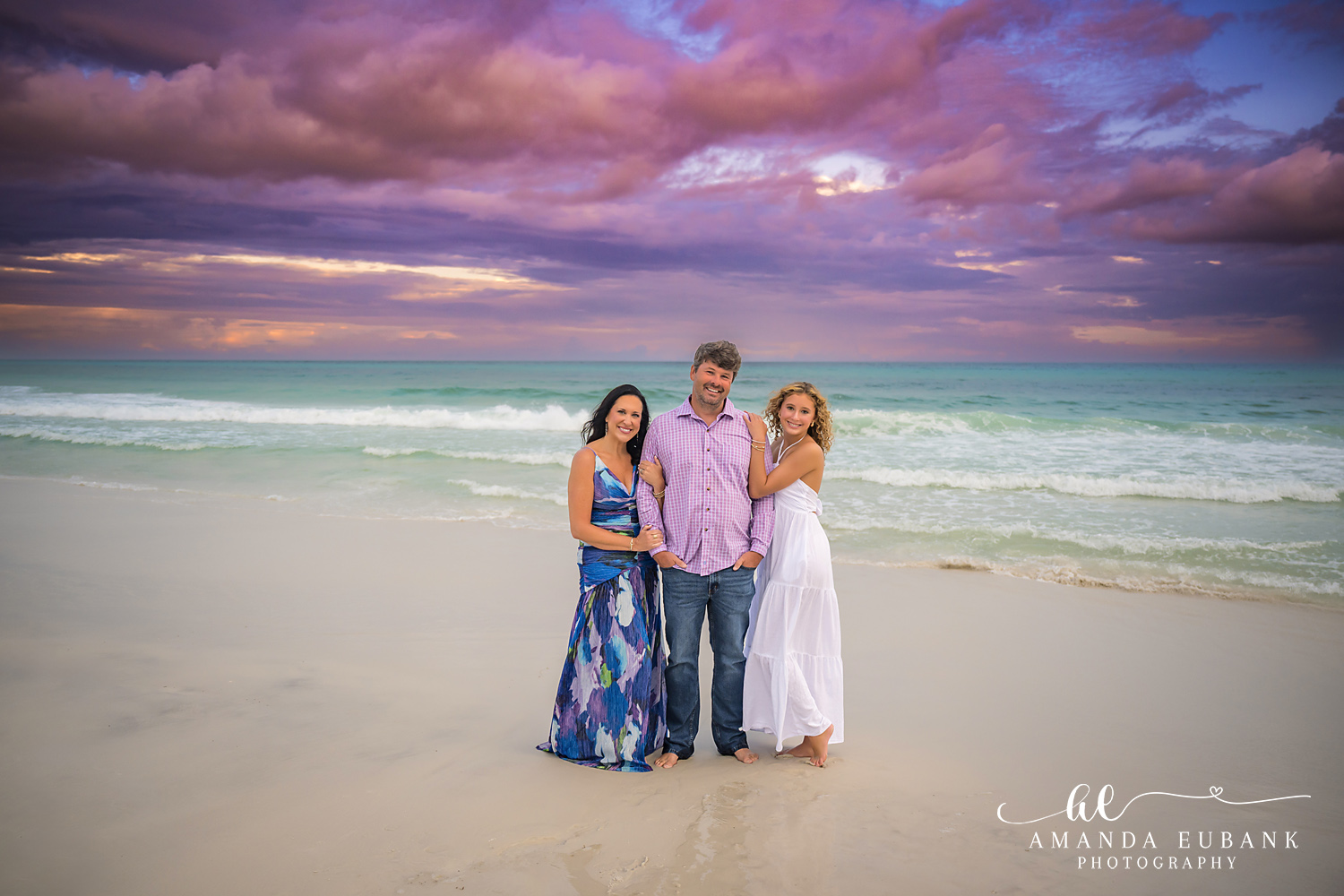 Family of Four Under Violet Clouds — Tampa, FL Family Session A family of four standing on the sand in navy and white beneath violet clouds at a beach family session near Tampa, Florida.