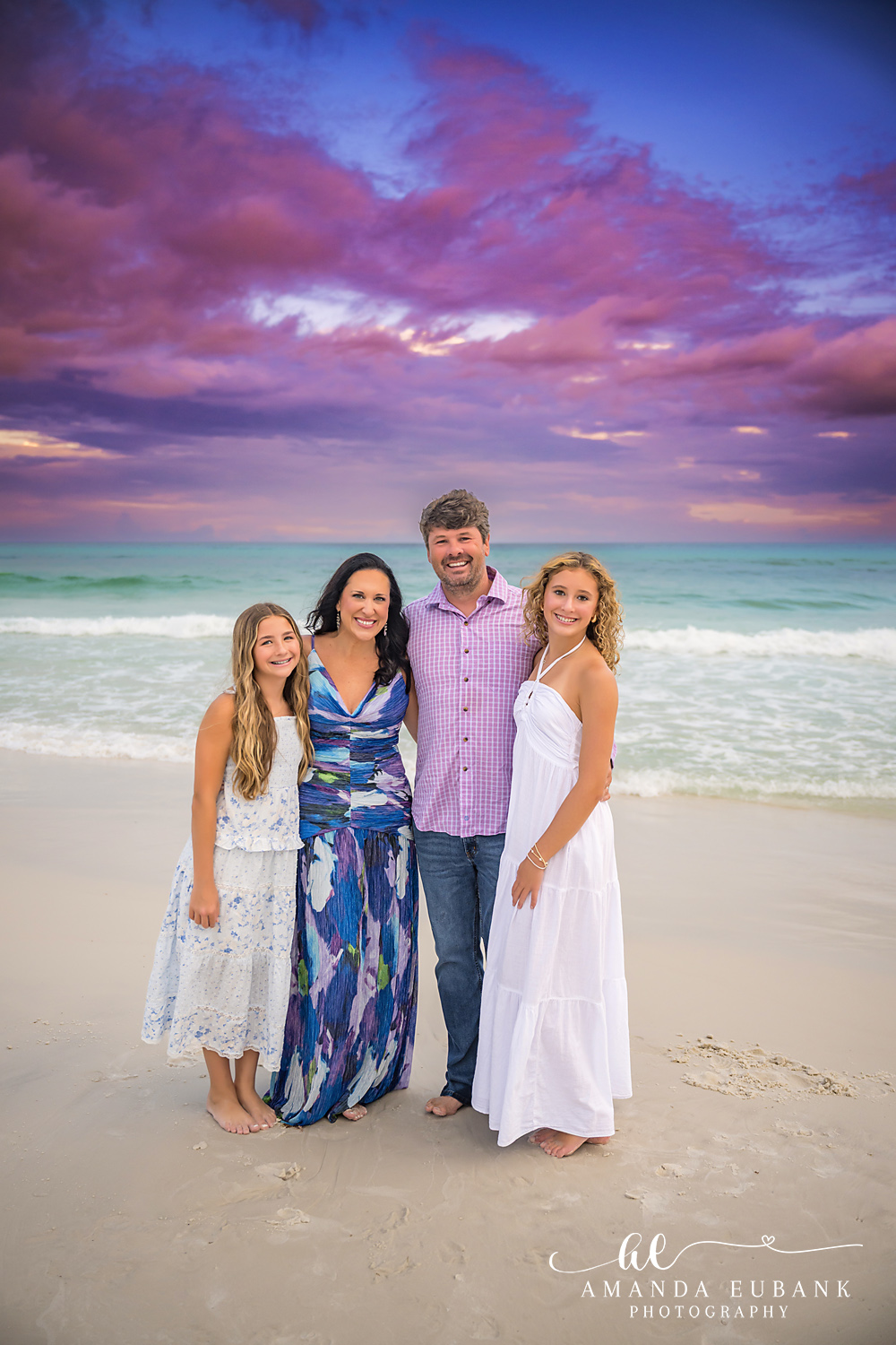Mother and Daughters in Navy | Family Photographer in Tampa, Florida Family beach portraits in Tampa, FL showing a mother and her daughters on the beach in navy and white under a purple sky.