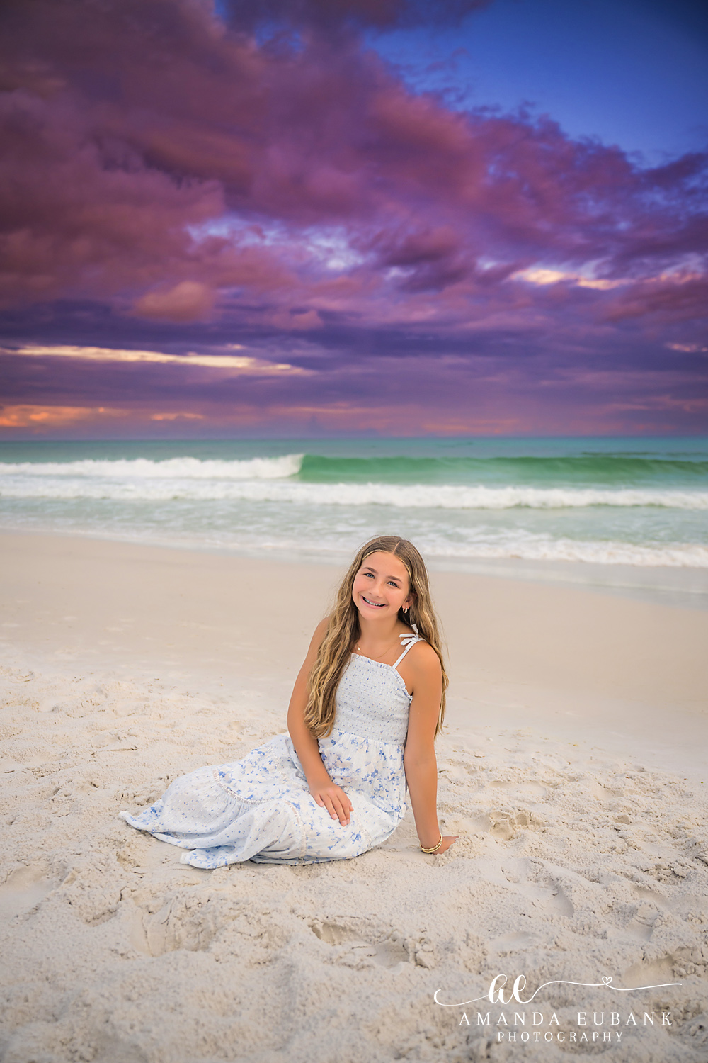 Portrait in a White Gown | Tampa Beach Family Photography Tampa family photographer captures a young woman in a white gown seated on the beach under a violet sky.