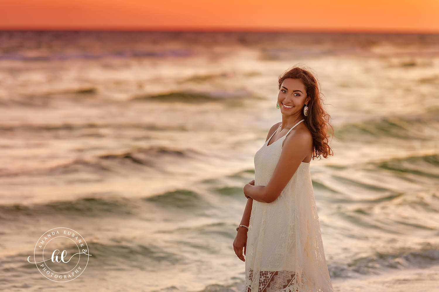Senior Portrait by the Waves | Senior Portraits in Tampa, FL Tampa senior photographer captures a senior in a cream dress standing by the breaking waves in warm evening light.