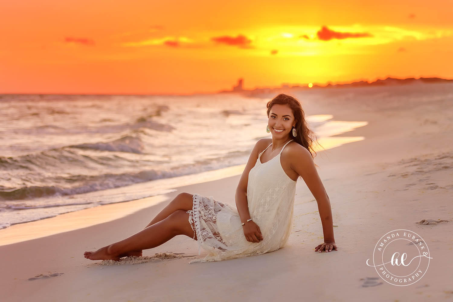 Senior Reclining on the Sand — Tampa Bay Senior Photography A senior in a white lace dress reclining on the sand under a blazing orange sky at a beach senior session in Tampa, FL.