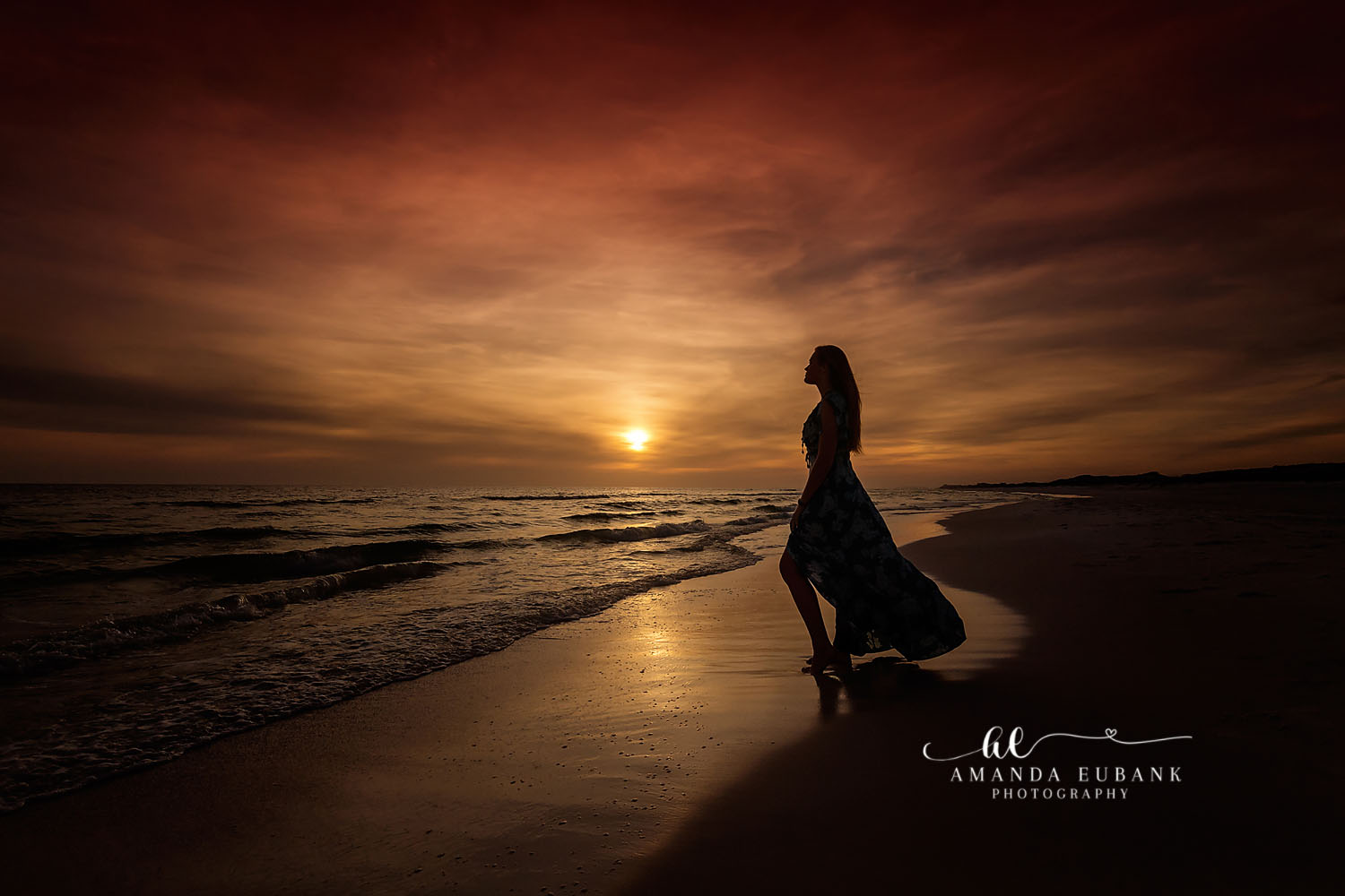 Silhouette in a Black Gown | Tampa Senior Photographer The silhouette of a senior in a black gown against a golden sun on the water during a senior portrait session in Tampa, Florida.