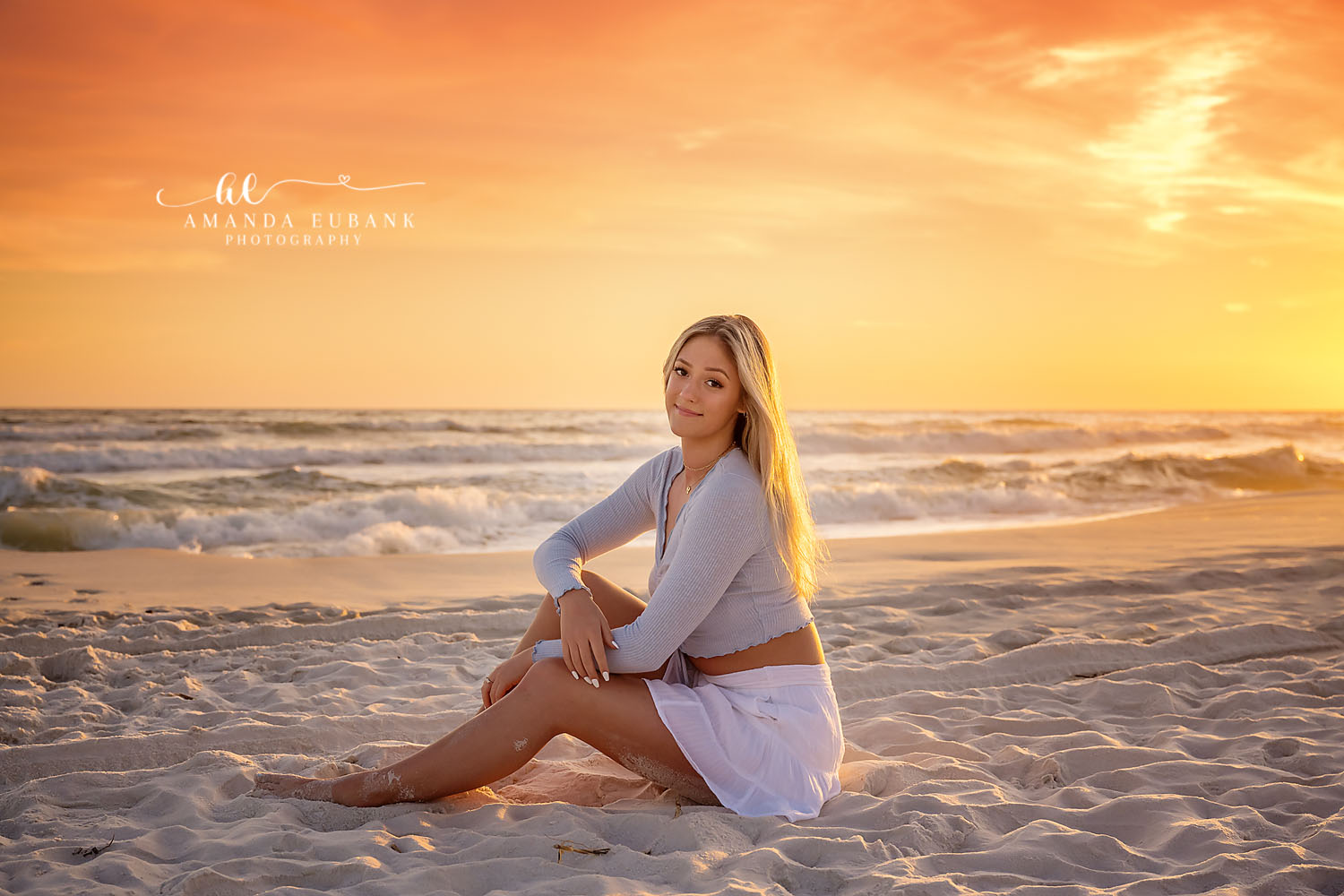 Senior Sitting in Golden Light | Tampa Senior Photographer A senior in white seated on the sand in warm golden evening light during a senior portrait session in Tampa, Florida.