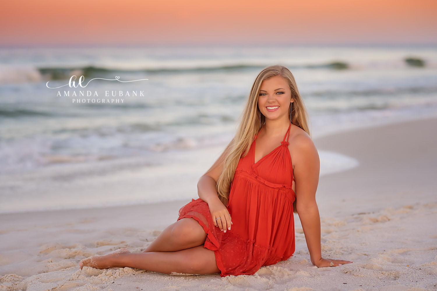 Red Dress in the Shallows — Tampa Bay Senior Photography A senior in a red dress seated in the shallow surf as waves roll in behind her at a beach senior session in Tampa, FL.