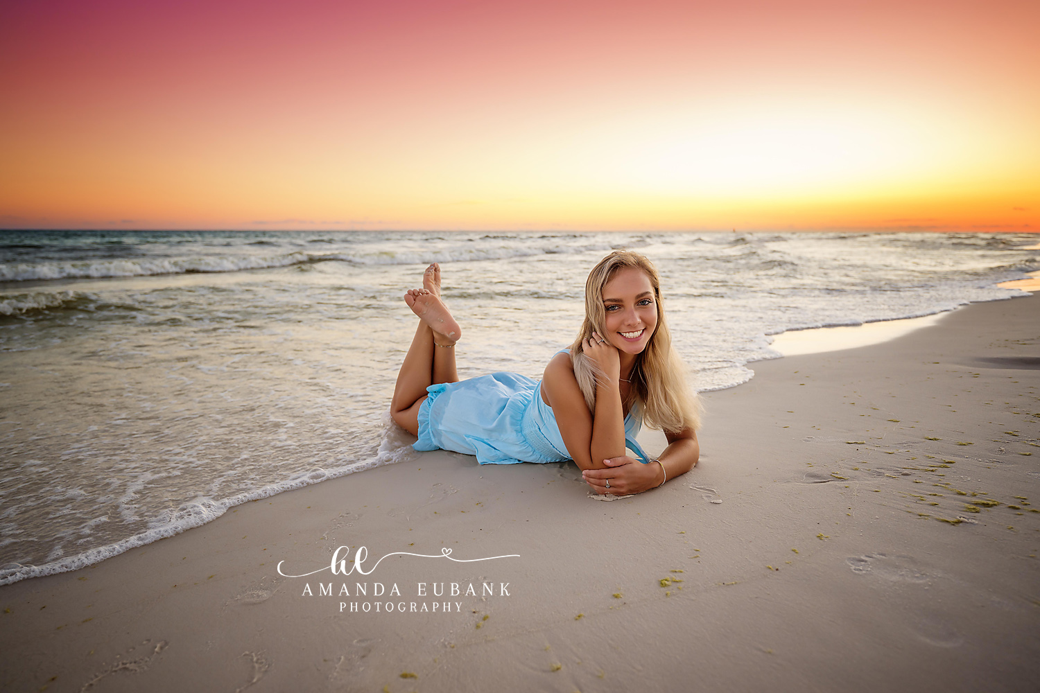 Blue Dress in the Sand | Tampa Senior Photographer A senior in a blue dress lying on the sand as the sun sets over the Gulf during a senior portrait session in Tampa, Florida.