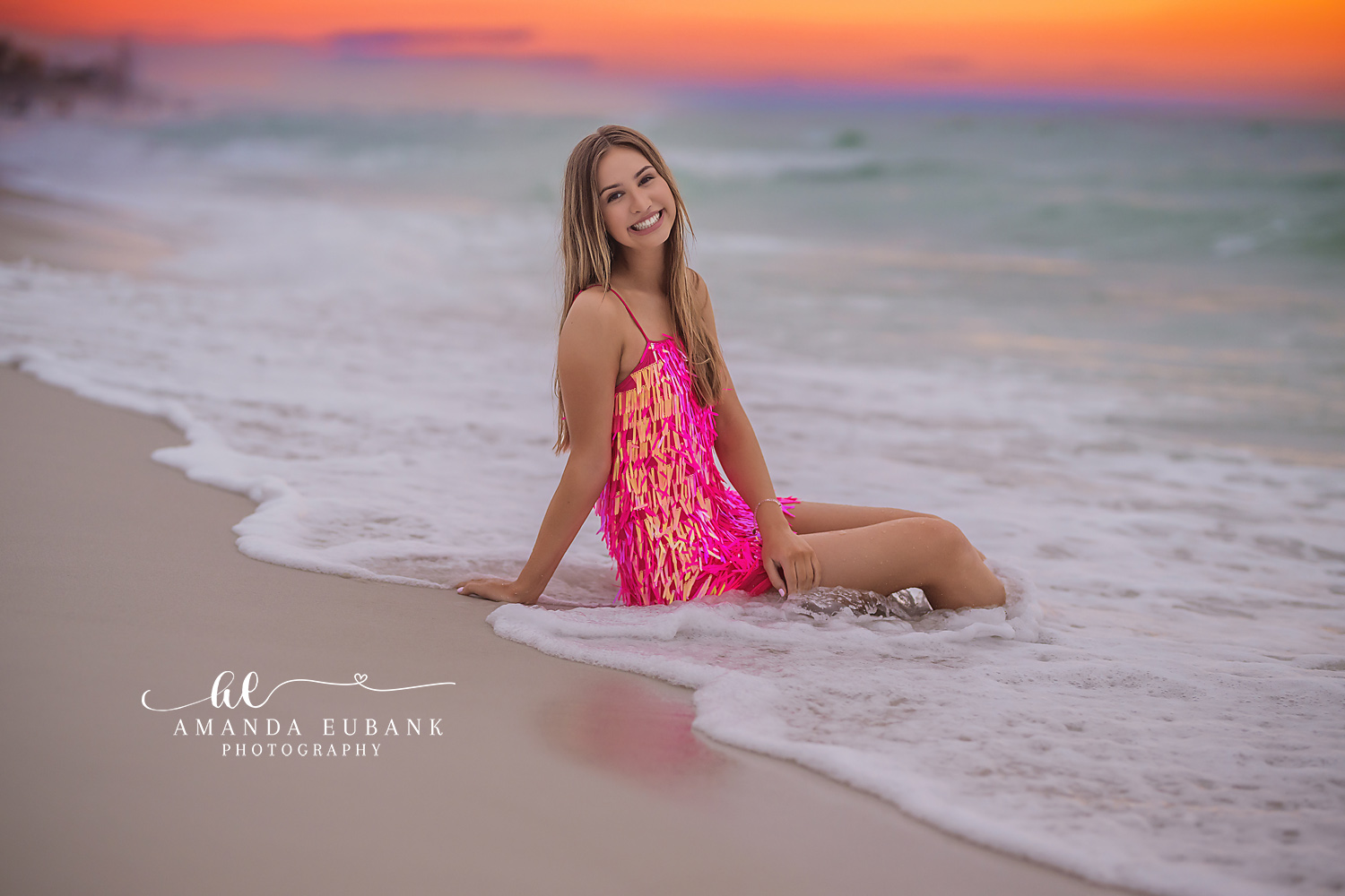 Pink Dress on the Wet Sand | Tampa Senior Photographer A senior in a pink patterned dress seated on the wet sand at coral sunset during a senior portrait session in Tampa, Florida.