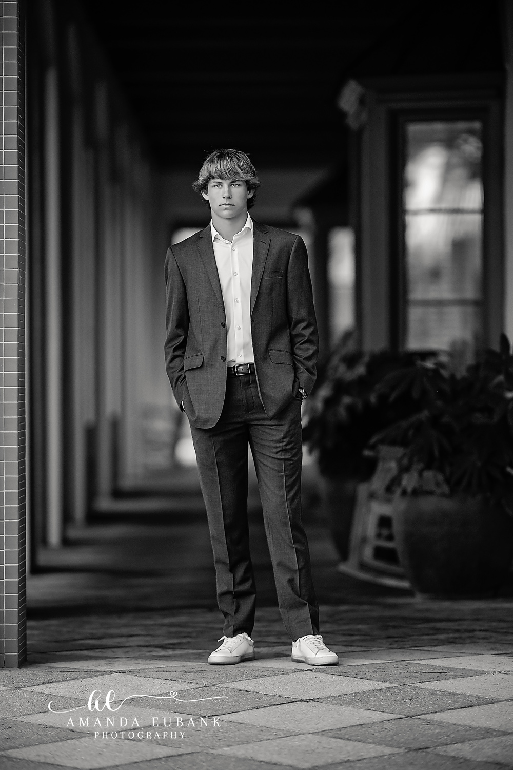 Suit Portrait in the Colonnade | Tampa Senior Photographer A black and white portrait of a senior in a suit standing in a stone colonnade during a senior session in Tampa, Florida.