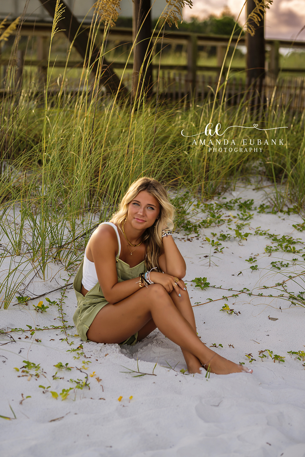 Seated in the Sea Oats | Tampa Senior Photographer A senior in a green dress seated in the sea oats beside a dune walkover during a senior portrait session in Tampa, Florida.