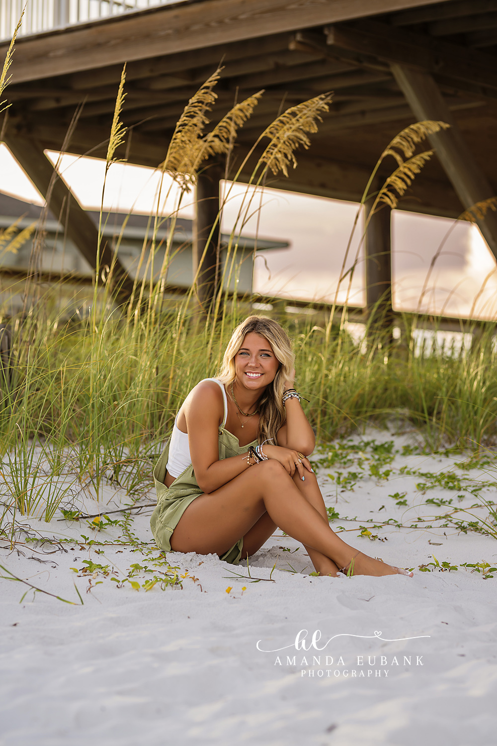 Under the Boardwalk | Senior Portraits in Tampa, FL Tampa senior photographer captures a senior seated in the dune grass beneath a wooden beach boardwalk.