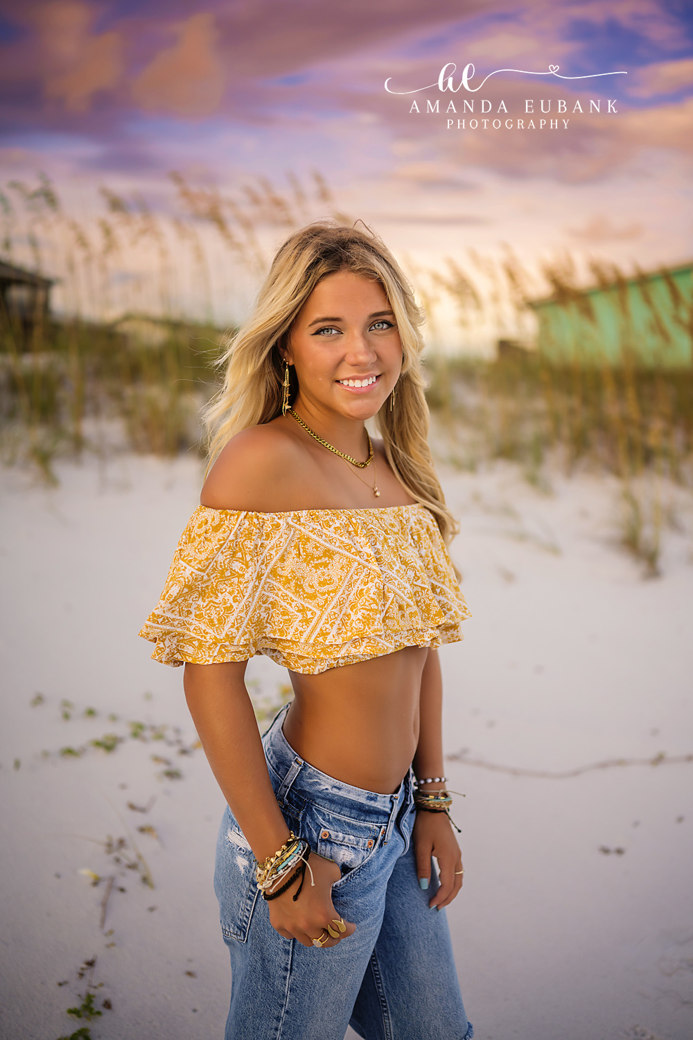 Yellow Top in the Dunes | Beach Senior Session in Tampa, Florida Senior pictures in Tampa Bay showing a senior in a yellow off-shoulder top and jeans standing in the dunes.