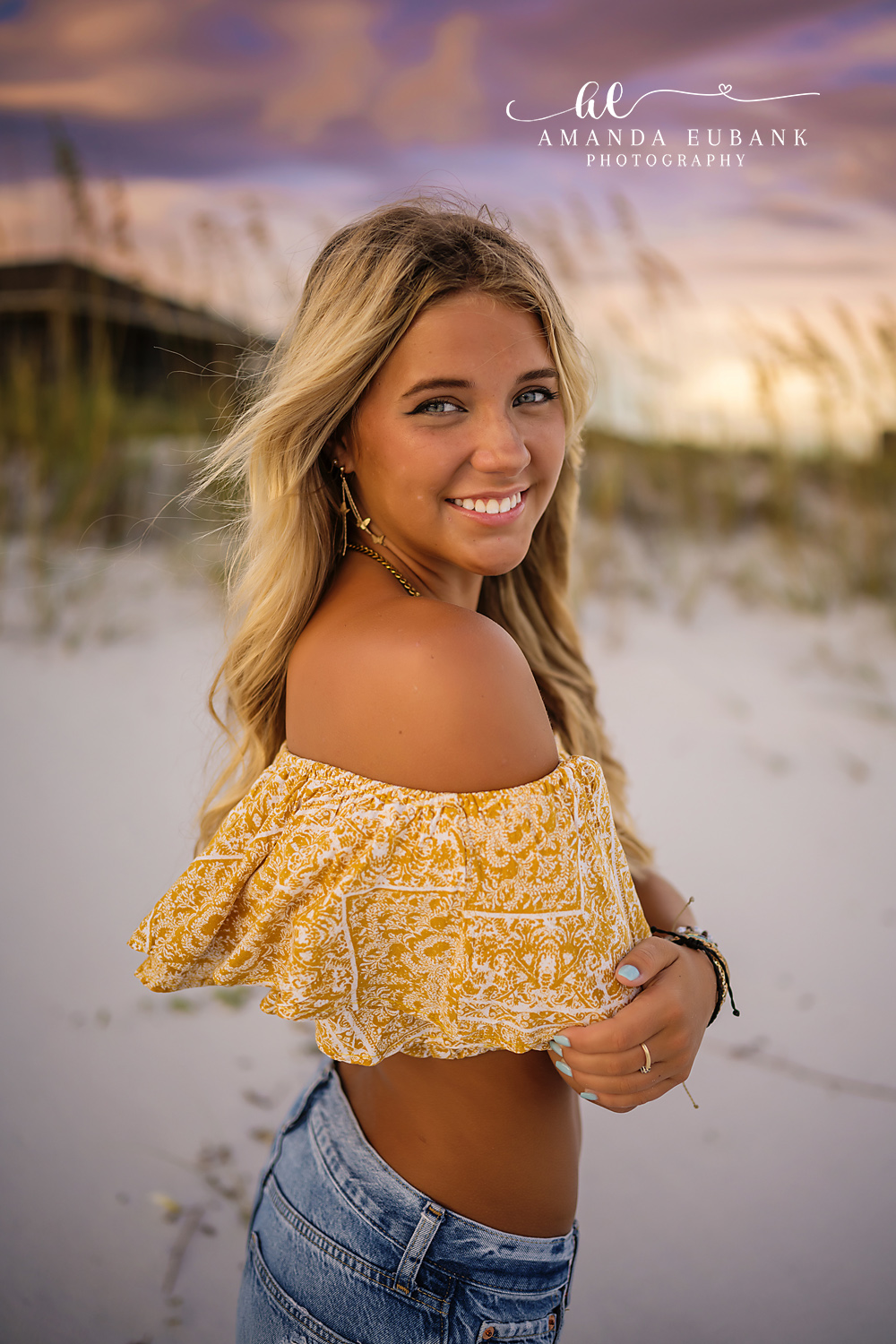 Laughing in the Dunes | Tampa Senior Photographer A laughing senior in a yellow top and jeans among the sea oats at dusk during a senior portrait session in Tampa, Florida.