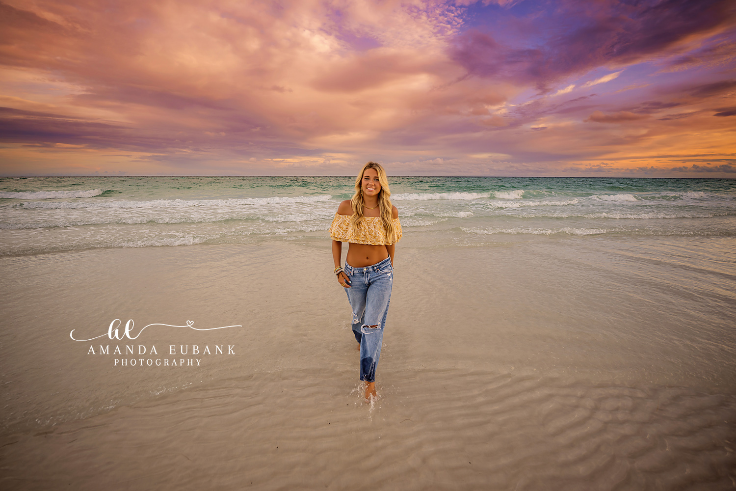 Walking the Reflective Sand | Beach Senior Session in Tampa, Florida Senior pictures in Tampa Bay showing a senior walking toward the camera on mirror-wet sand under a purple sky.