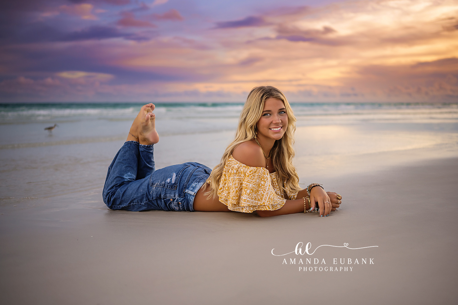 Lying on the Shoreline — Tampa Bay Senior Photography A senior lying on the wet sand in a yellow top under a pastel evening sky at a beach senior session in Tampa, FL.