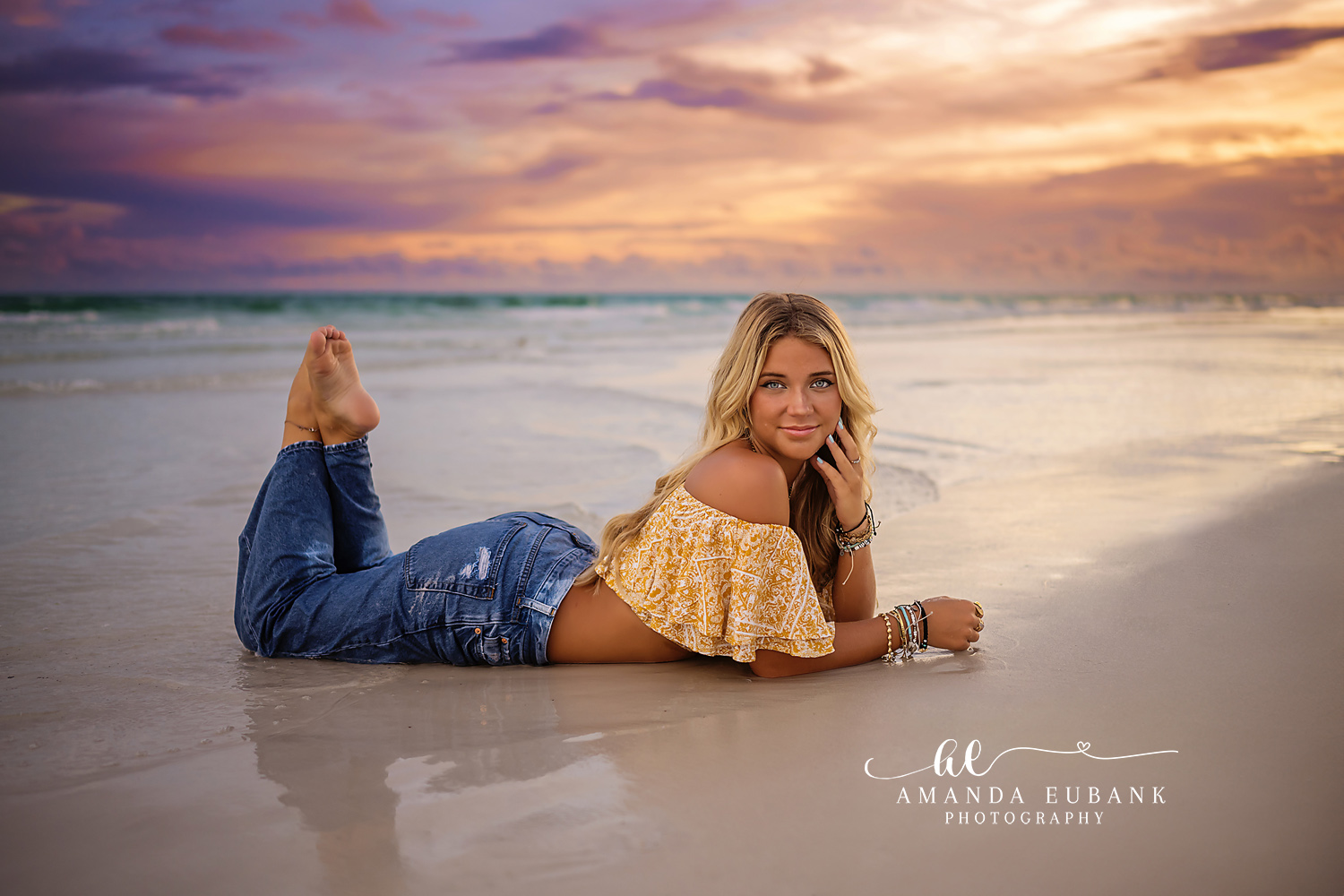 Denim and Gold at Sunset | Beach Senior Session in Tampa, Florida Senior pictures in Tampa Bay showing a senior lying on the wet sand in denim and a gold top under a gold sky.