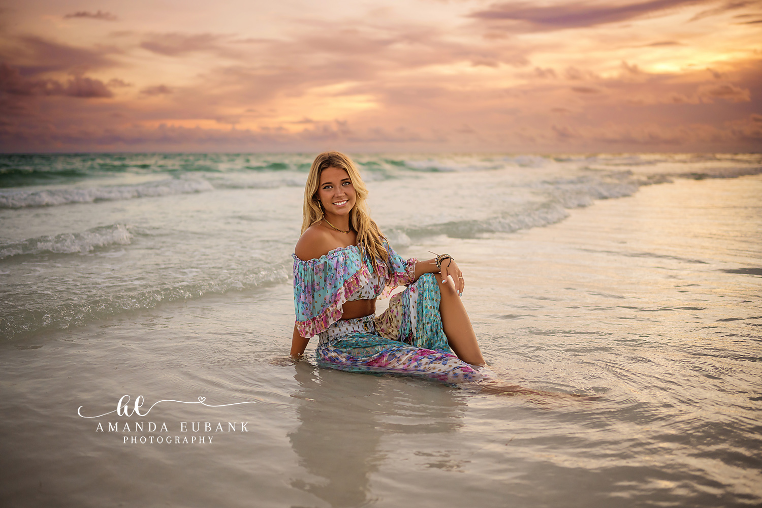 Seated in the Warm Shallows | Beach Senior Session in Tampa, Florida Senior pictures in Tampa Bay showing a senior in a floral dress seated in the warm shallows at golden hour.