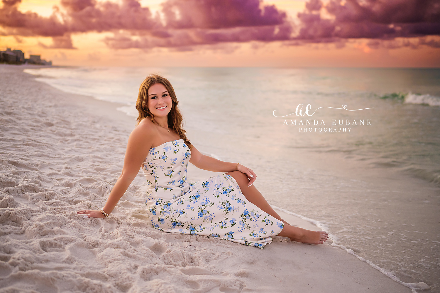Floral Dress on the Sand | Senior Portraits in Tampa, FL Tampa senior photographer captures a senior in a white floral dress seated on the sand under a purple sky.