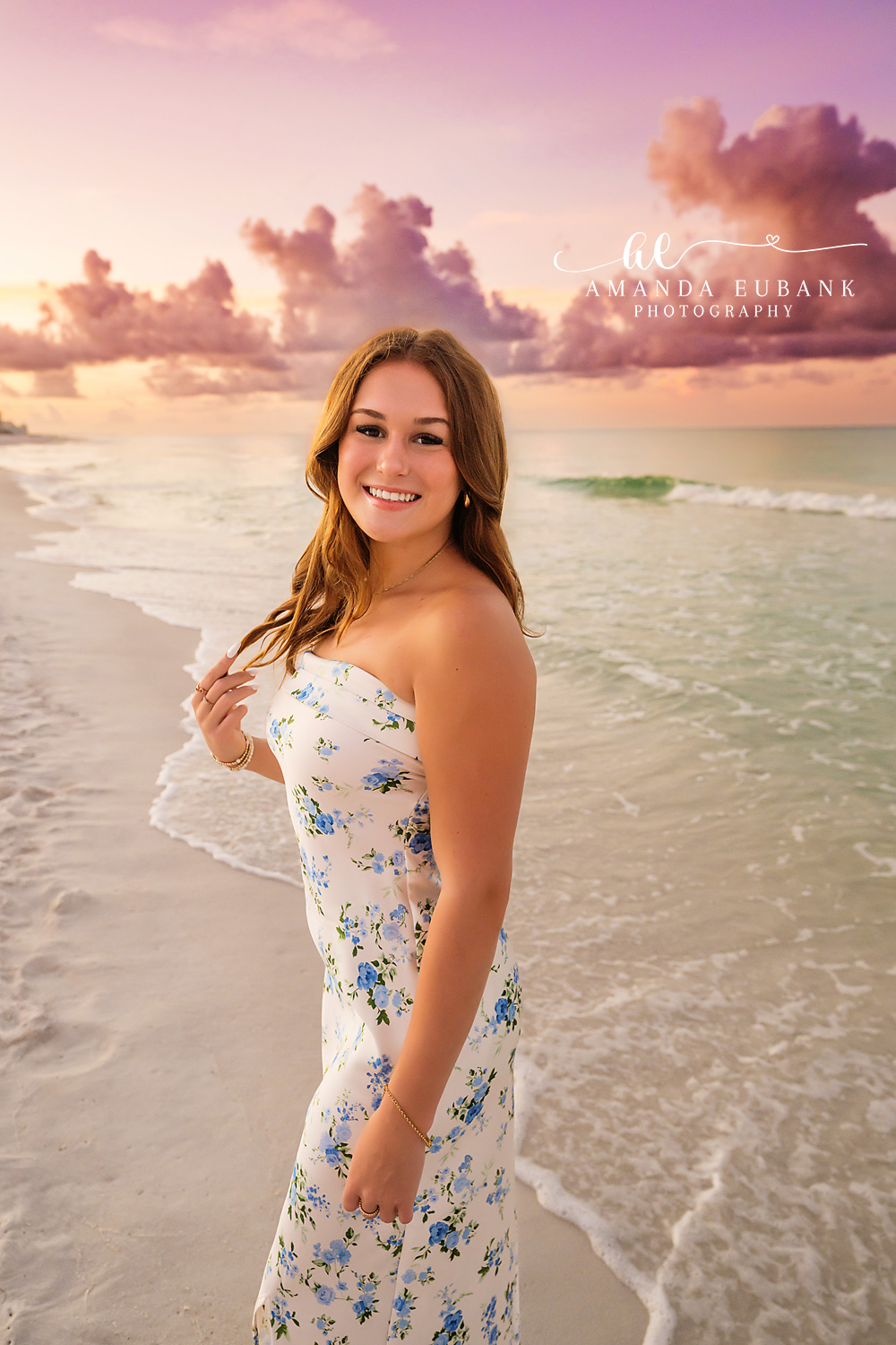 Standing in the Gulf Shallows — Tampa Bay Senior Photography A senior in a white floral dress standing in the shallows under pink clouds at a beach senior session in Tampa, FL.